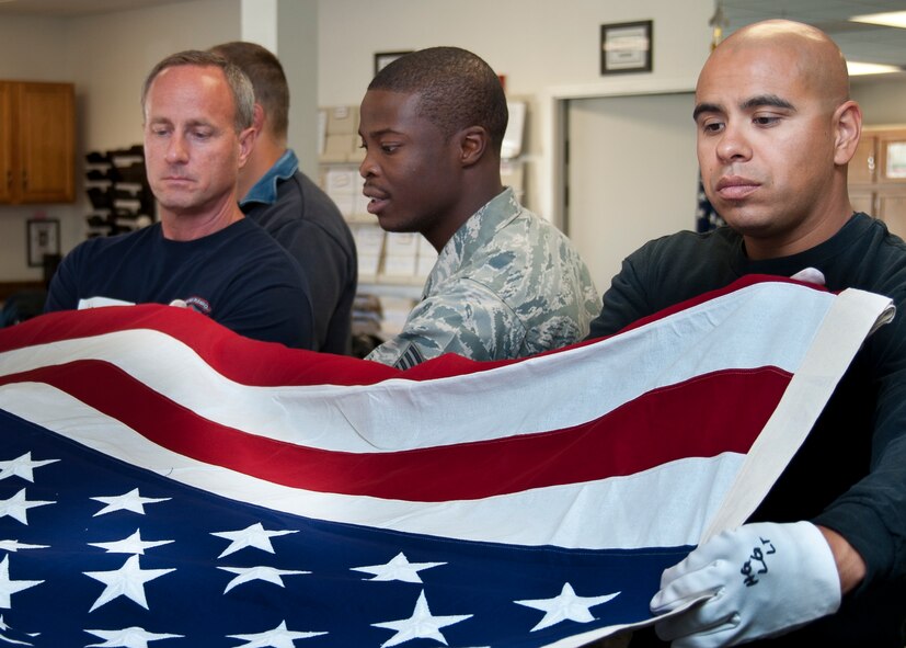 Firefighter John Vargas Livermore-Pleasanton Fire department (right) and Dectective Richardeo Hernadez, Tracy Police Department (left) practice the six man flag fold with Honorguardsman instructor SSgt Gary Willams, (middle) from 60 Arial Port Squadron, Travis Air Force Base 23 Oct. 2012. Personnel from local police and fire departments were on hand 22-26 October 2012 at Travis Air Force Base to recieve short but intense training in Funeral Party ceremony.  (Released - U.S. Air Force Photograph/Heide Couch)