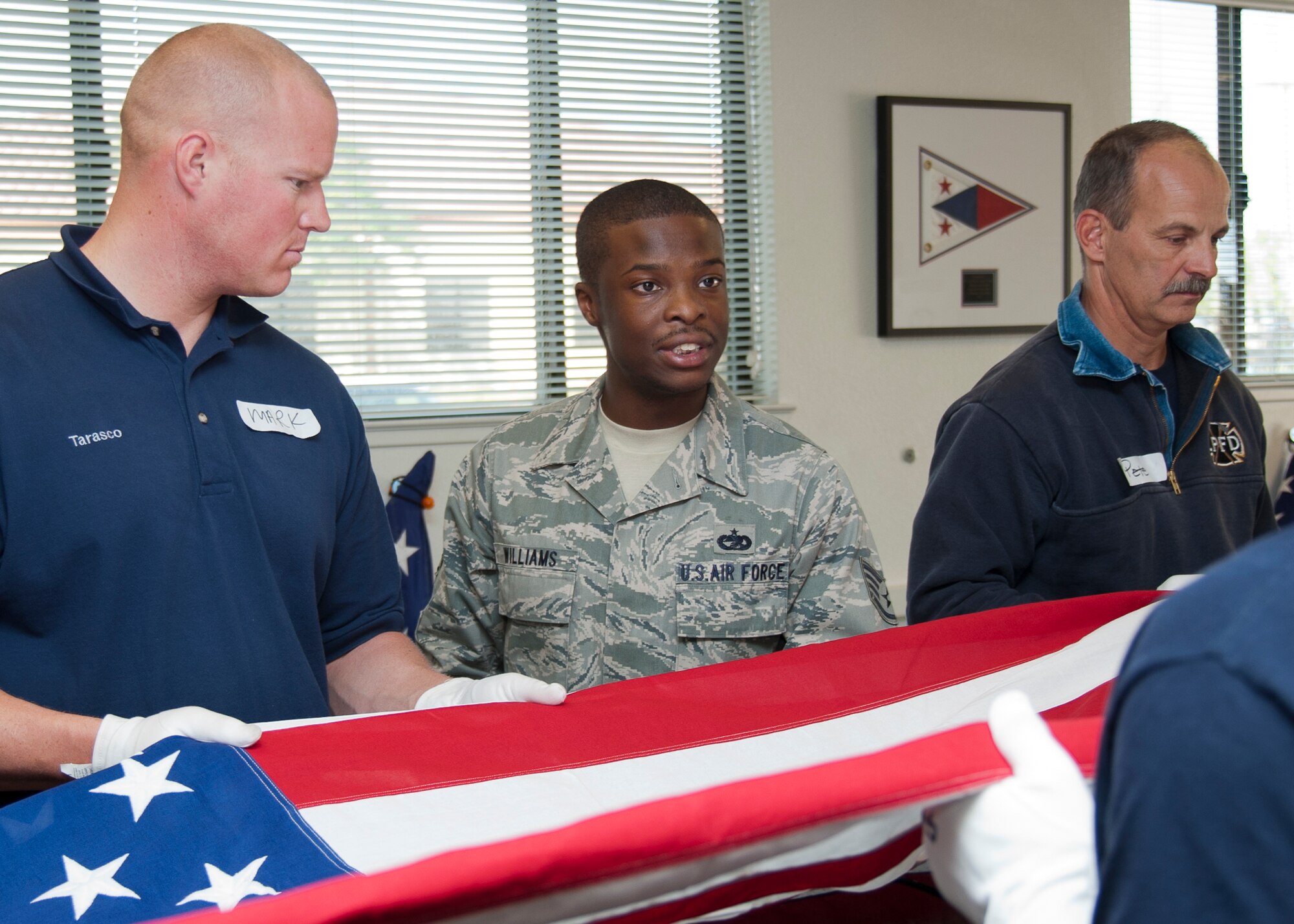 Officer Mark Tarasco, Gilroy Police Department (right) and Captain Peter Richert, Livermore-Pleasanton Fire Department (left) practice the six man flag fold with Honorguardsman instructor SSgt Gary Willams, (middle) from 60 Arial Port Squadron, Travis Air Force Base 23 Oct. 2012. (Released - U.S. Air Force Photograph/Heide Couch)