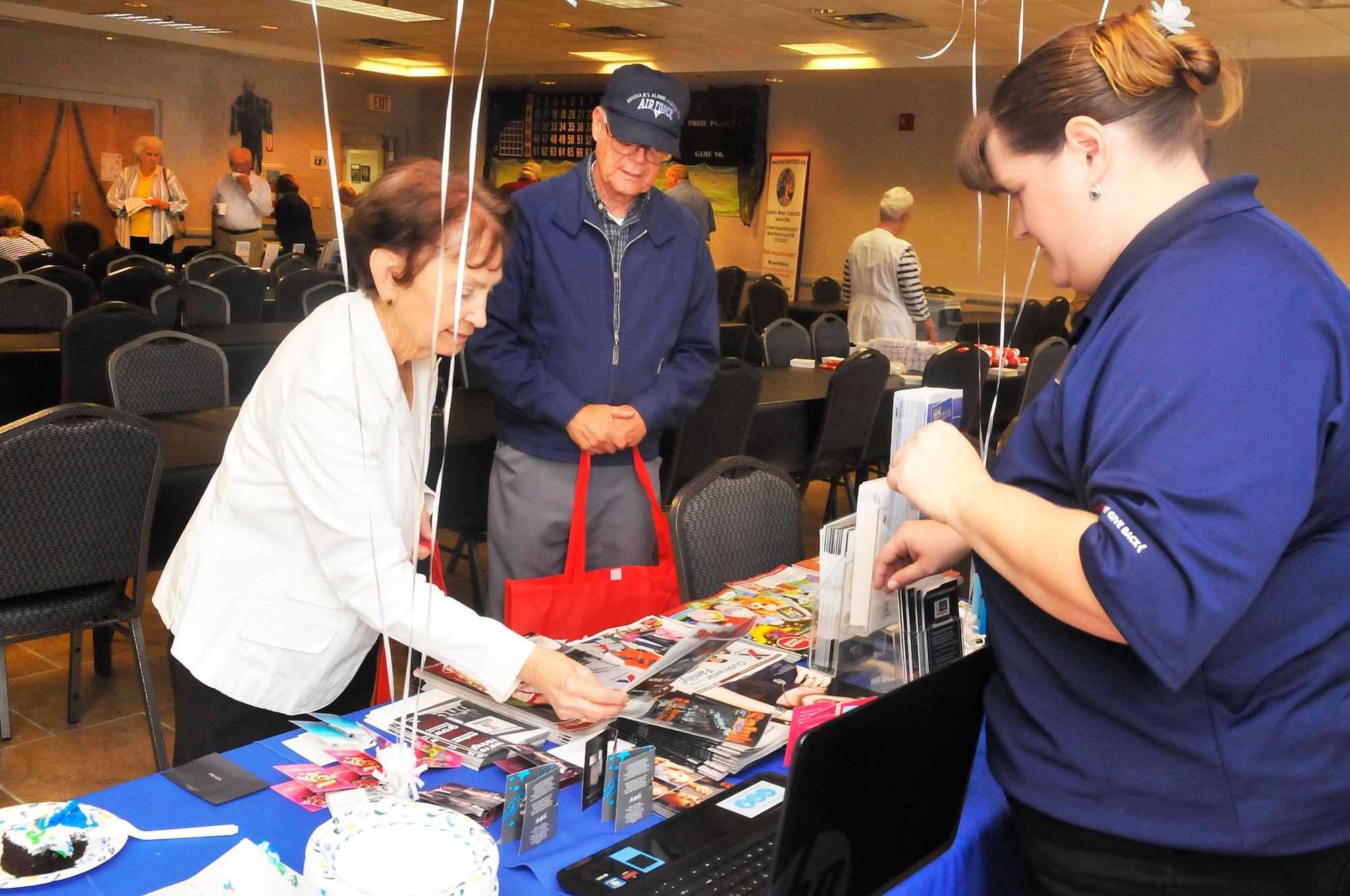 Retired Air Force Chief Master Sgt. Gene Salyer and his wife Betty, at left, gather some information from Bobbie Harmon at the Base Exchange table  during Robins’ Retiree Appreciation Day, Saturday, for military retirees from all branches of service and their guests.The appreciation day was to inform, assist and honor all retired military members, spouses and surviving spouses, and their family members with base access. (U. S. Air Force photo/Sue Sapp)