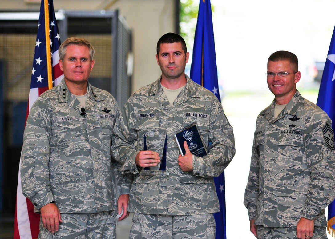 Master Sgt. Thomas Webster of the 919th Operations Group Detachment 2, center, clutches two major awards presented to him recently by Lt. Gen. Eric Fiel, the commander of Air Force Special Operations Command, left, and Chief Master Sgt. William Turner, AFSOC's command chief, at Duke Field, Fla.  Webster was named the 2011 Outstanding Air Force Reserve Component Intelligence, Surveillance and Reconnaissance Senior NCO and 2011 Outstanding Air Force ISR Senior NCO. (U.S. Air Force photo/Tech. Sgt. Cheryl Foster)