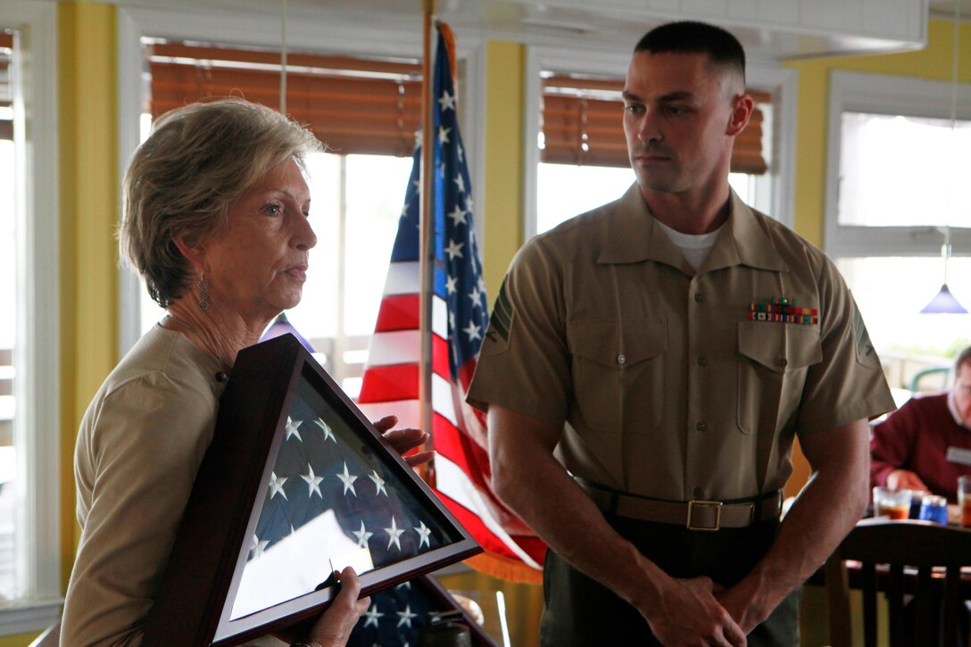 A member of the Carteret County Chamber of Commerce Military Affairs Committee presents Sgt. Michael Brawn with an American flag during a ceremony Oct. 26 in Atlantic Beach, N.C., to recognize Brawn as the committee’s Service Person of the Quarter. Brawn is an ordnance instructor at the Center for Naval Aviation Technical Training at Marine Corps Air Station Cherry Point.