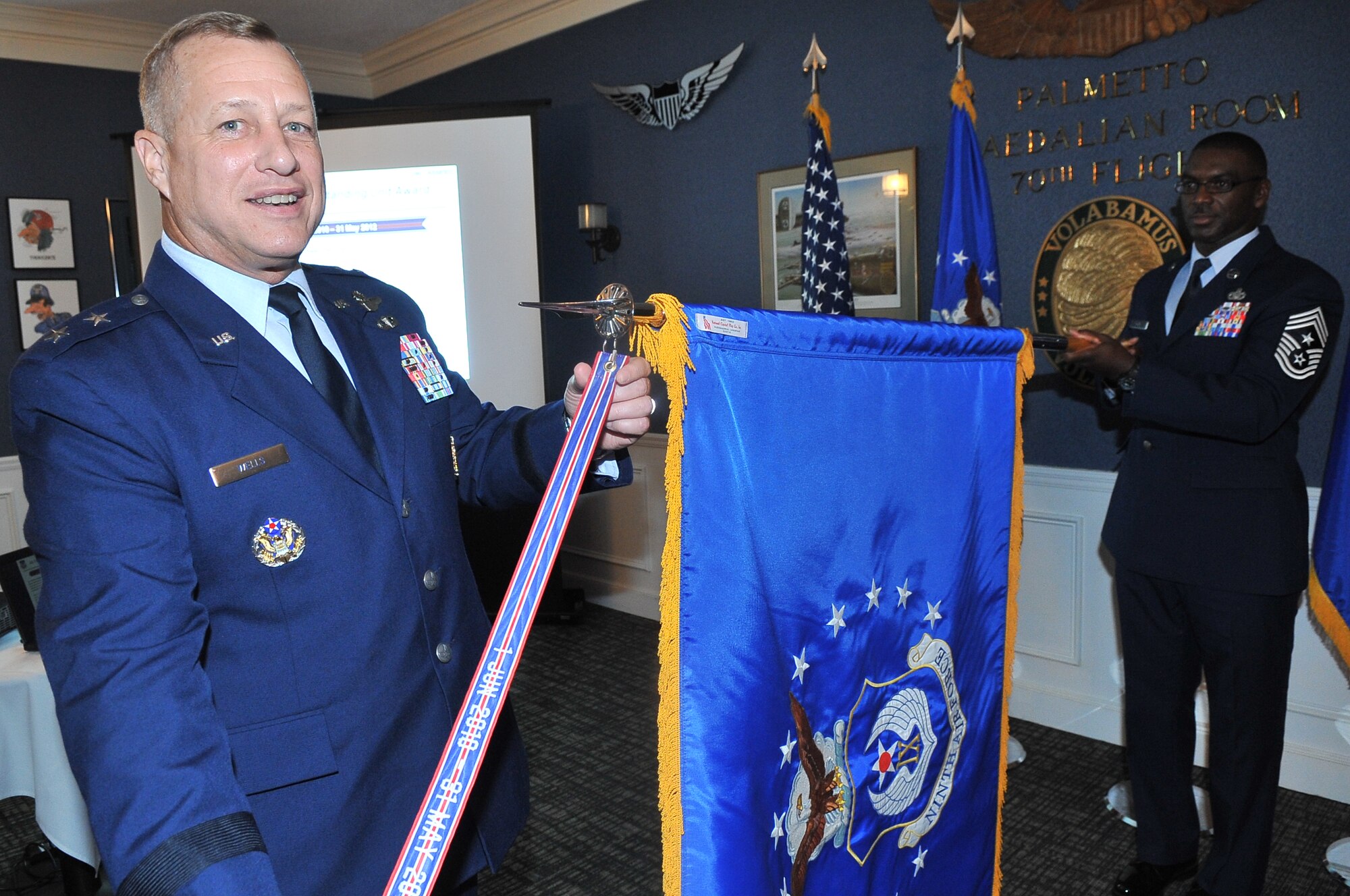 Maj. Gen. Lawrence Wells, 9th Air Force commander, attaches the Air Force Outstanding Unit Award streamer to the 9th AF unit flag during a commander's call at the Carolina Skies Club, Shaw Air Force Base, S.C., Oct. 26, 2012.
The streamer-pinning ceremony marked the unit's first-ever receipt of the Air Force Outstanding Unit Award, an honor awarded to numbered units in recognition of exceptionally meritorious service or outstanding achievement.
(U.S. Air Force photo by Airman 1st Class Ashley Gardner/Released)
