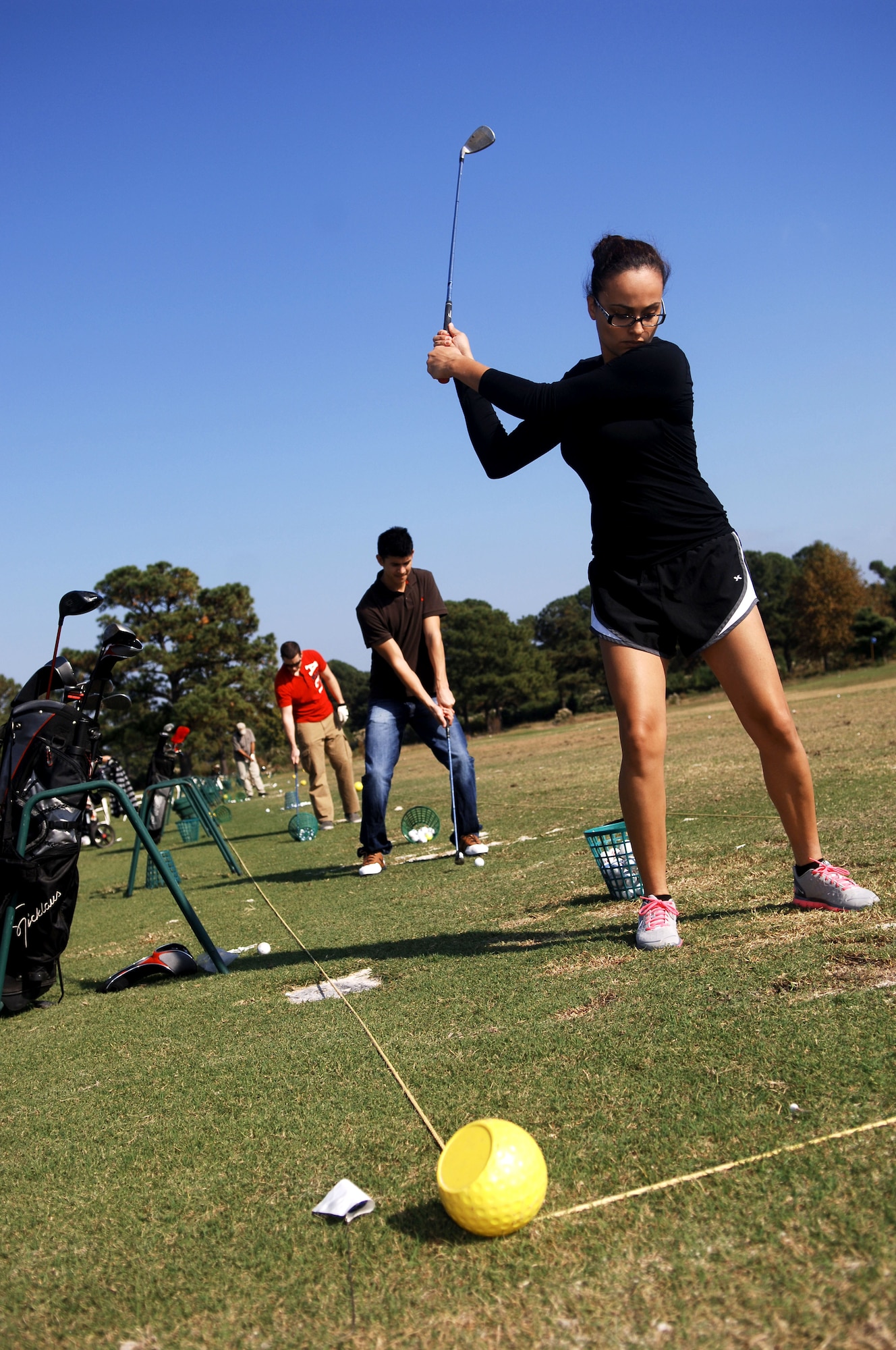 Members practice their golf swings at the Eaglewood Golf Course driving range, Oct. 25, 2012 at Langley Air Force Base, Va.  The Eaglewood Golf Course offers day-and-night driving ranges, and no charge for rental clubs for senior airmen and below.  (U.S. Air Force photo by Staff Sgt. Katie G. Ward / Released)