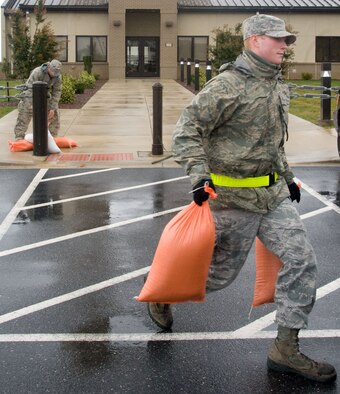 Airman 1st Class Richard Stratton, from the 436th Civil Engineer Squadron, and Senior Airman Robert Fitch, from the 436th Aerial Port Squadron, collect sandbags from outside of building 502 Oct. 30, 2012, at Dover Air Force Base, Del. The sandbags were placed at entrances around the base in preparation for Hurricane Sandy. (U.S. Air Force photo by Adrian R. Rowan)