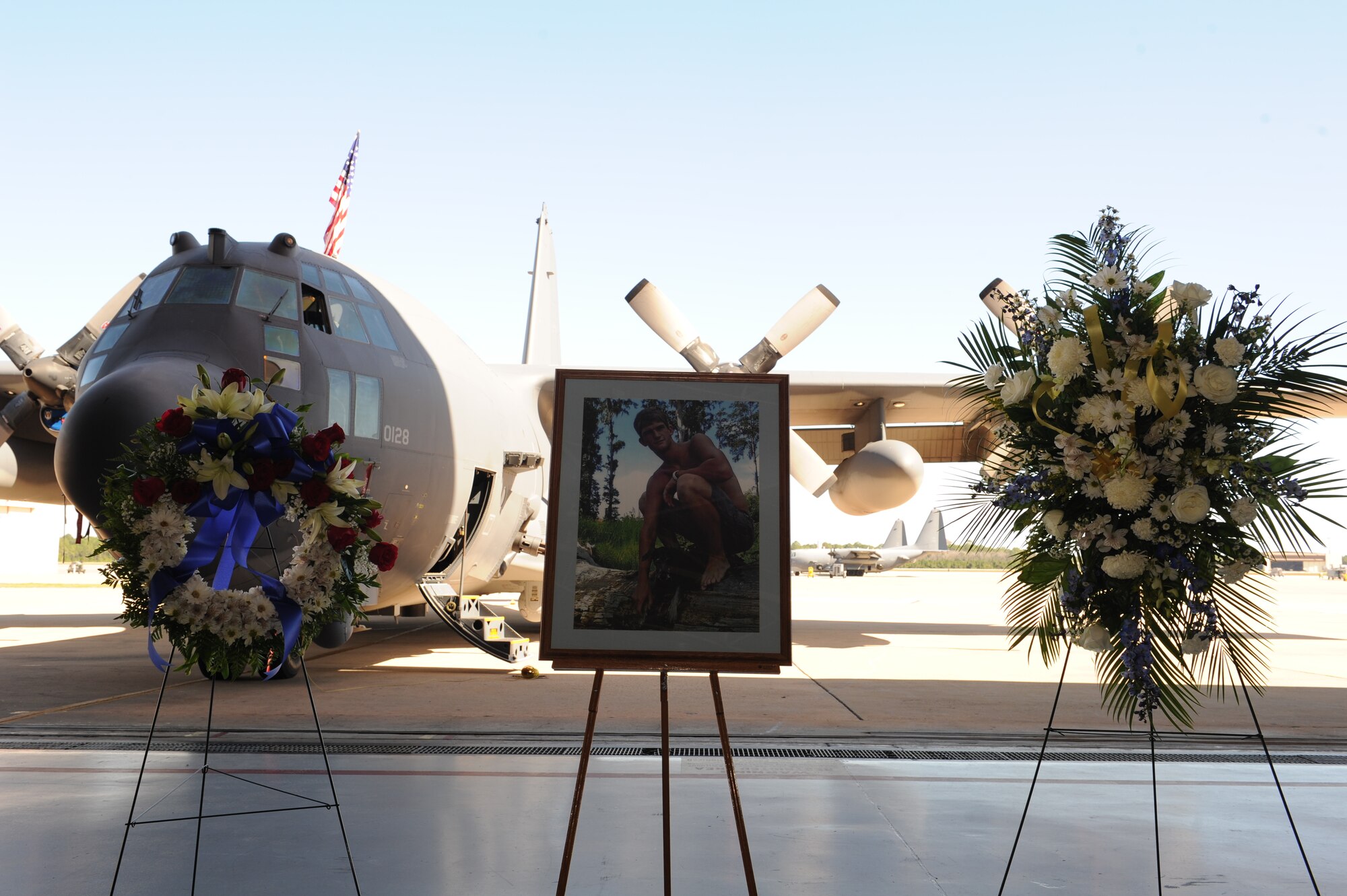 A memorial photo of Airman 1st Class Colby Graham Siegel, an aerospace propulsion apprentice with 1st Special Operations Aircraft Maintenance Squadron, is flanked by two floral arrangements next to an AC-130H Spooky gunship during a memorial ceremony at the Commando Hangar at Hurlburt Field, Oct. 25, 2012. Siegel passed away Oct. 21, 2012 during a boating mishap in the Santa Rosa Sound, Fla. (U.S. Air Force photo / Senior Airman Eboni Reams)(Released)