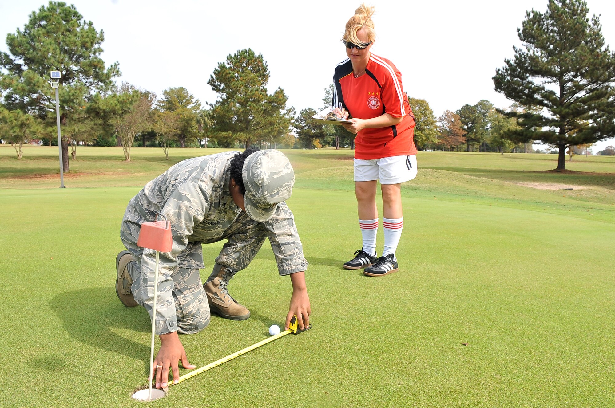 U.S. Air Force 2nd Lt. Latisha Cannon (left) and 1st Lt. Renea Skelton, 20th Force Support Squadron, check to see how far a participant’s golf ball is away from the hole during a Halloween golf tournament, Shaw Air Force Base, S.C. Oct. 26, 2012. The tournament was held to help raise money for holiday events. (U.S. Air Force photo by Airman 1st Class Ashley L. Gardner/Released)