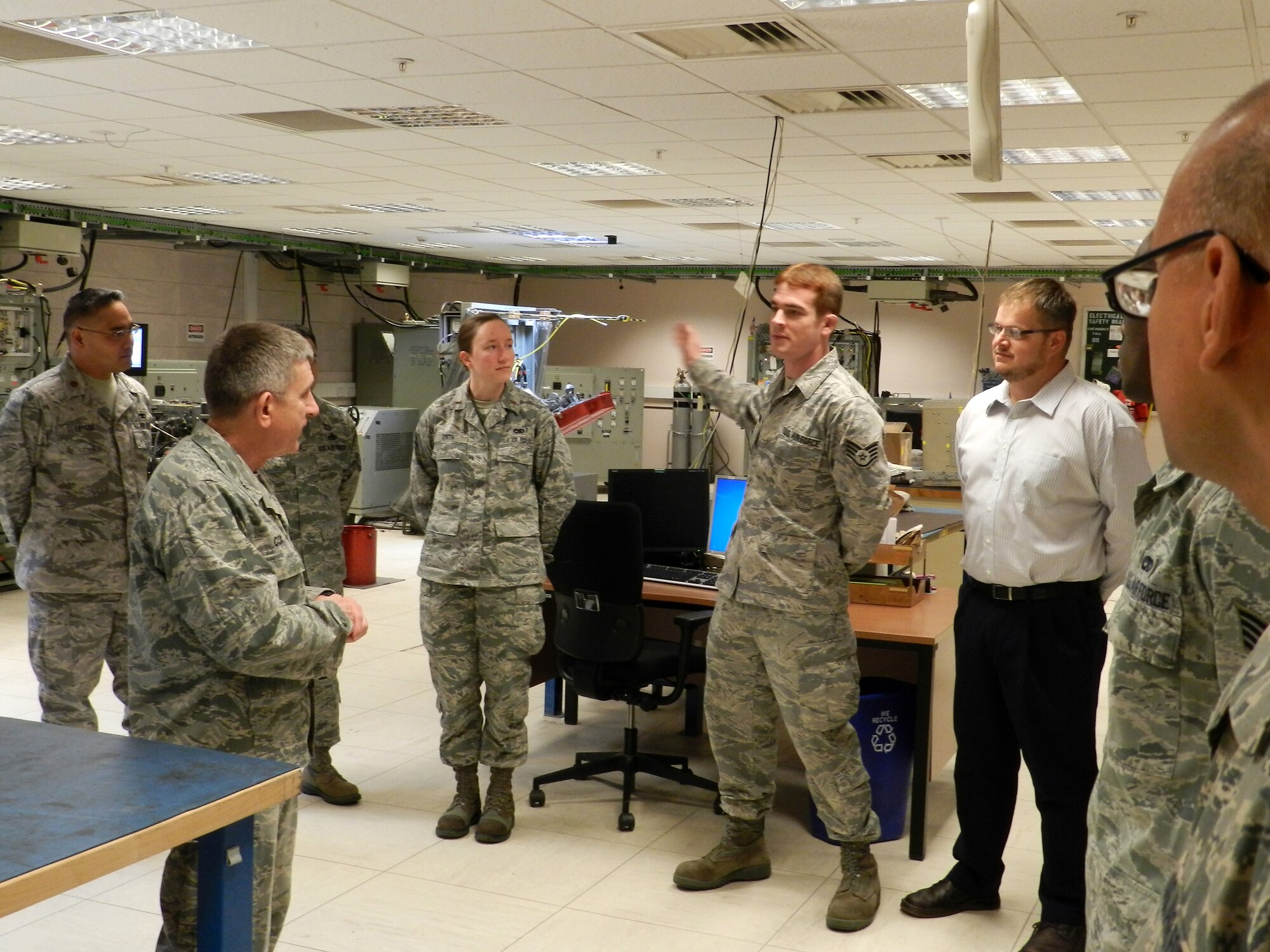 ROYAL AIR FORCE LAKENHEATH, England -- Staff Sgt. Joshua Simmons (center), 48th Component Maintenance Squadron avionics team leader, briefs Col. Matthew Cox (front left), 48th Maintenance Group commander, at a ribbon cutting event Oct. 10, 2012 signifying the 48th CMS Avionics Intermediate Section?s return to 100 percent fully mission-capable test station status. The final test station to be repaired passed all self-tests the day prior. (Courtesy photo)