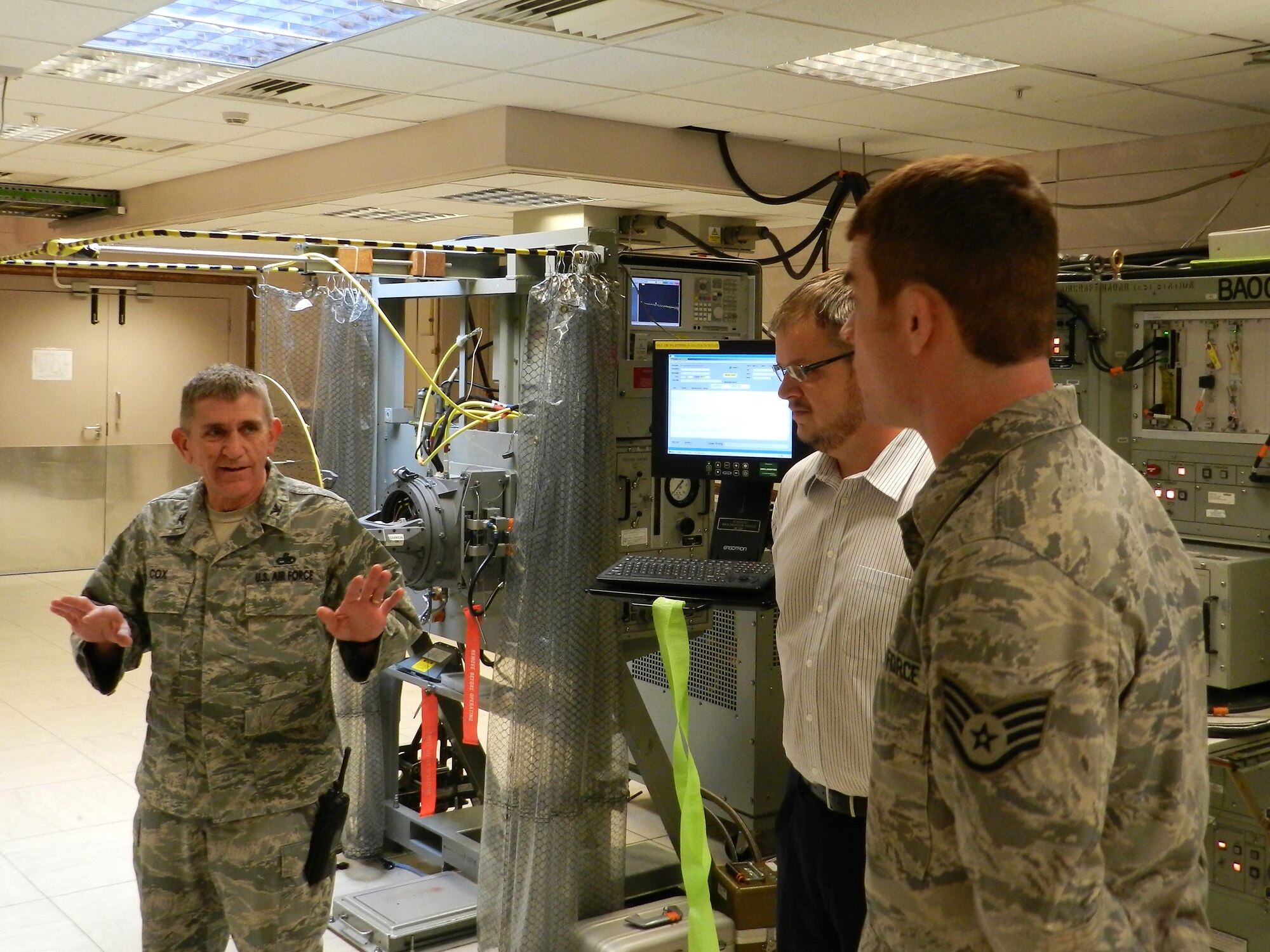 ROYAL AIR FORCE LAKENHEATH, England -- Col. Matthew Cox (left), 48th Maintenance Group commander, speaks with Dan Foraker (center), 48th Component Maintenance Squadron equipment specialist, and Staff Sgt. Joshua Simmons, 48th CMS avionics team leader, after cutting a ribbon Oct. 10, 2012 signifying the 48th CMS Avionics Intermediate Section?s return to 100 percent fully mission-capable test station status. Foraker and Simmons formed a dedicated team and spent two weeks repairing, calibrating and verifying the final broken test station. (Courtesy photo)