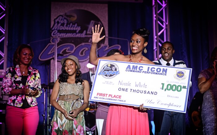 1Lt. Nicole White, from Scott Air Force Base, accepts her first place award after performing for a crowd of more than 200 at the Scott Air Force Base club Oct. 25, 2012. Ten performers participated in the 2012 AMC Icon, a contest similar to the famed American Idol in which contestants competed for cash prizes and a spot to perform in the U.S. Air Force Tops in Blue group. 1Lt. Nicole White took the top prize with Staff Sgt. Tiry Crane as the runner up and TSgt Doug Boren in third place. (U.S. Air Force photo/ Staff Sgt. Ryan Crane)