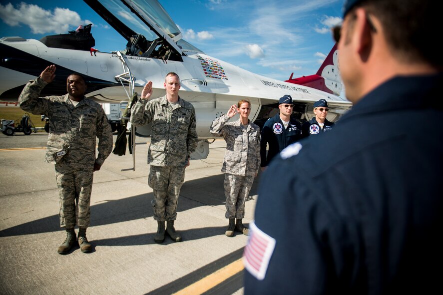 U.S. Air Force Master Sgt. Amory Witcher, 23d Medical Support Squadron, Tech. Sgt. Alex Griffin, 23d Wing Public Affairs, and Staff Sgt. Andrea Burke, 23d Communications Squadron, recite the Oath of Enlistment during a re-enlistment ceremony at the Moody Air Force Base, Ga., Legacy of Liberty Open House air show Oct. 26, 2012. Lt. Col. Greg Moseley, U.S. Air Force Thunderbird 1, commander, administered the ceremony. (U.S. Air Force photo by Staff Sgt. Jamal D. Sutter/Released)