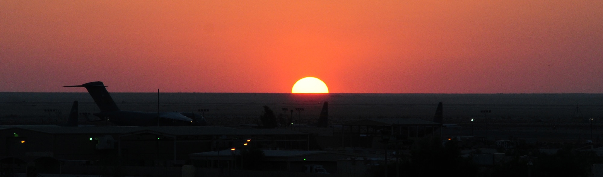 SOUTHWEST ASIA – The sun sets over the flightline at a deployed location in Southwest Asia, Oct. 9. The aircraft, a C-130 Hercules and a C-17 Globemaster, are awaiting clearance for takeoff. Both are U.S. Air Force airlift aircraft capable of conducting a variety of missions including troop movement, cargo transport and medical evacuation of injured military personnel. The smaller C-130 has the added capability of taking off and landing on shorter, unprepared runways often found at remote forward operating bases. (U.S. Air Force photo/Staff Sgt. Alexandra M. Boutte) 