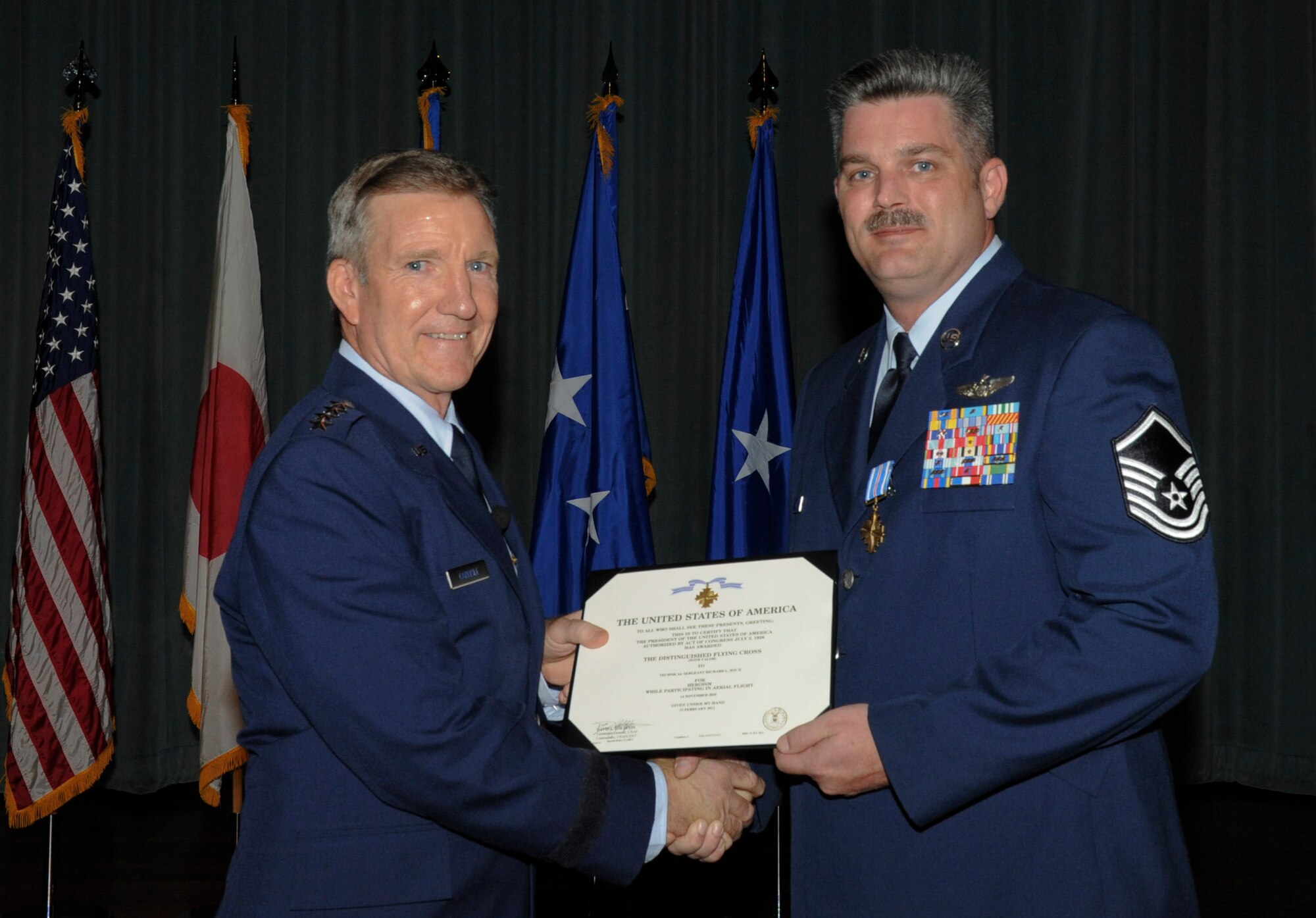 U.S. Air Force Master Sgt. Richard Joy, 33rd Rescue Squadron aerial gunner, is awarded the Distinguished Flying Cross medal by U.S. Air Force Gen. Herbert J. Carlisle, Pacific Air Forces commander, on Kadena Air Base, Japan, Oct. 29, 2012. While deployed to Bagram Air Base, Afghanistan in 2010, Joy performed a precision hover and hoist on extreme mountainous terrain under direct enemy fire. Without Joy's actions, many of the men on the mission would not have survived. (U.S. Air Force photo/Airman 1st Class Malia Jenkins)