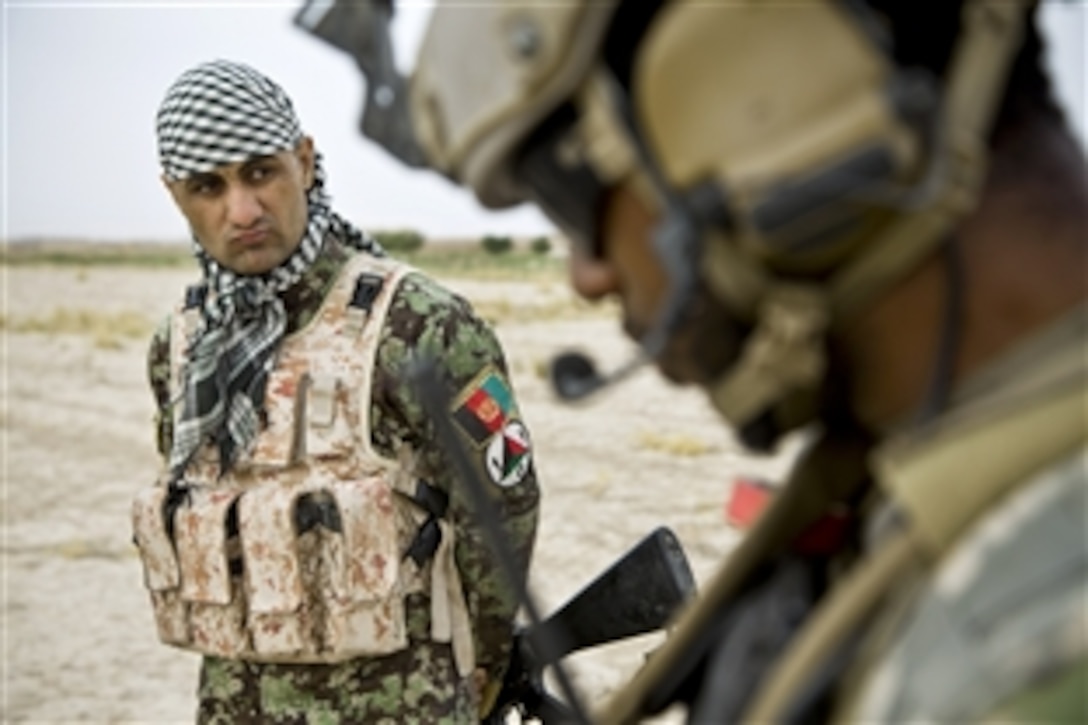 An Afghan soldier watches a coalition force member use his radio during an Afghan-led security patrol to deny the enemy freedom of movement in Khak-E-Safed in Afghanistan's Farah province, Oct. 30, 2012. Afghan forces have been taking the lead in security operations, with coalition forces as mentors, to bring security and stability to the country's residents.