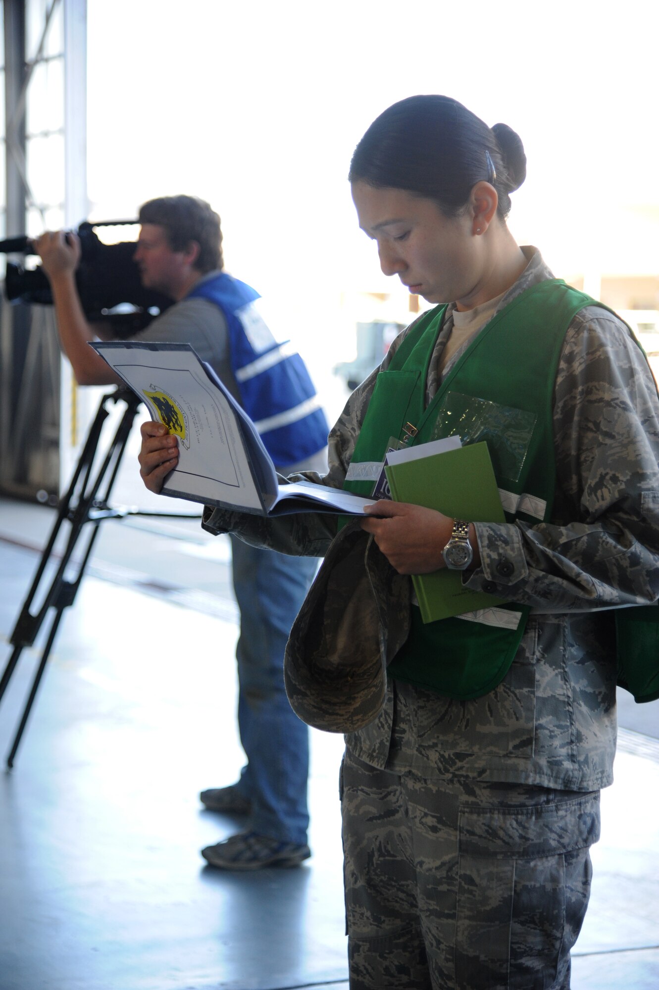 First Lt. Cindy Thuli, Air Education and Training Command inspector general team member, evaluates Keesler team members while Matt Hames, 81st Training Wing Public Affairs, takes video footage during a hazardous material and major accident response exercise Oct. 31, 2012, at Hangar 4, Keesler Air Force Base, Miss.  The exercise scenario consisted of a group of Airmen cleaning inside the hangar in preparation for demolition when a shelf holding old munitions fell to the ground causing one to break open, explode and splash an “oily substance” on several of the “victims.”  The exercise helped prepare first responders in the event of a real-world incident.  (U.S. Air Force photo by Kemberly Groue)
