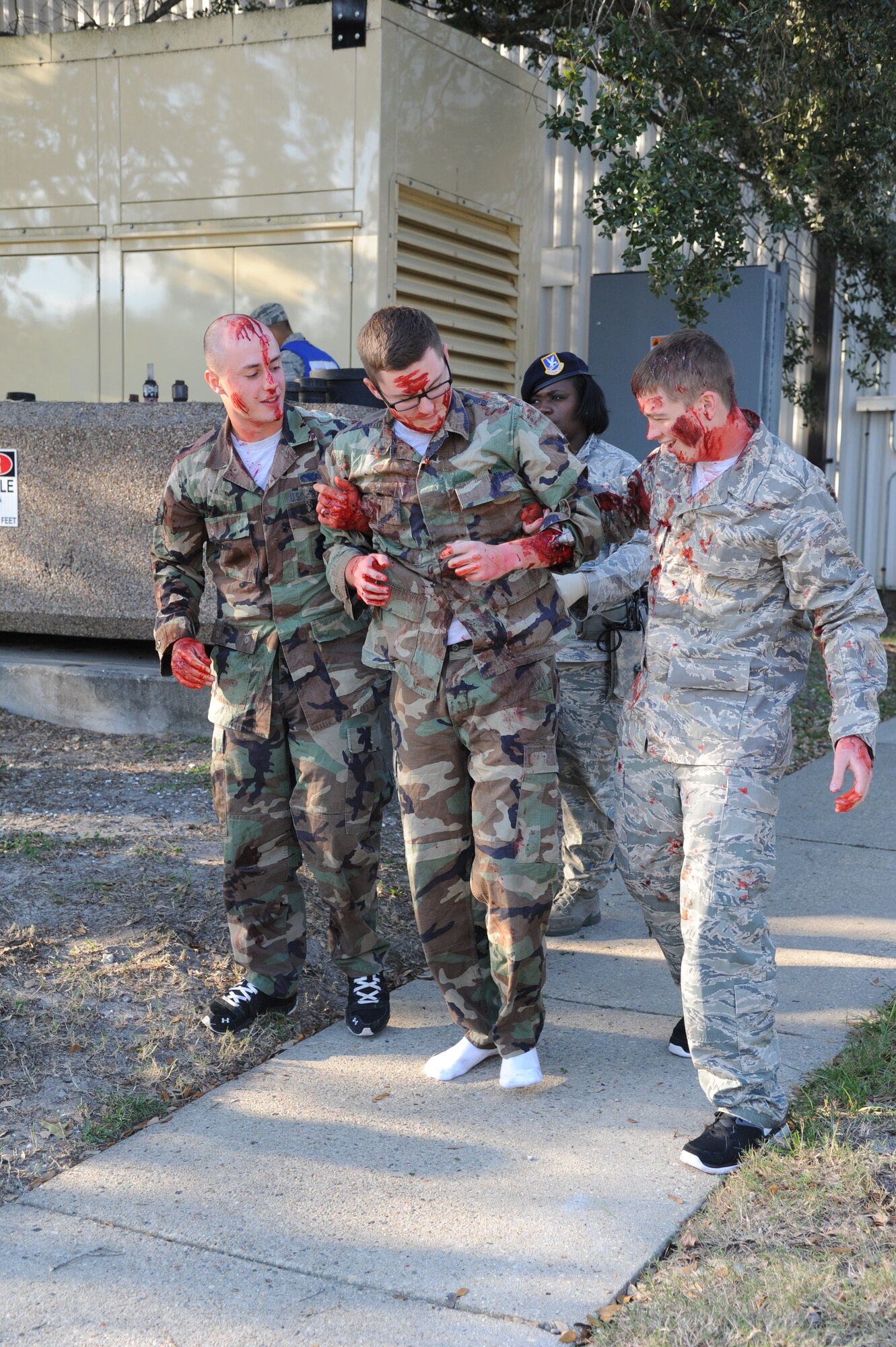 Airman Basic Brandon Johnson, Airman 1st Class Nathaniel Lanaghan and Airman Joshua Roumph, 336th Training Squadron, portray “victims” and assist each other in walking away from the contaminated area during a hazardous material and major accident response exercise Oct. 31, 2012, at Hanger 4, Keesler Air Force Base, Miss.  The exercise scenario consisted of a group of Airmen cleaning inside the hangar in preparation for demolition when a shelf holding old munitions fell to the ground causing one to break open, explode and splash an “oily substance” on several of the “victims.”  The exercise helped prepare first responders in the event of a real-world incident.  (U.S. Air Force photo by Kemberly Groue)