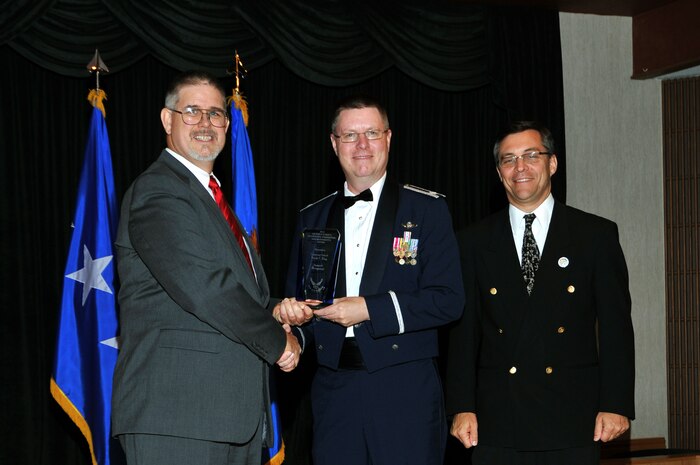 David Walker, Secretary of the Air Force Acquisitions deputy, and Mark Maybury, Science, Technology, and Engineering USAF chief scientist, present Lt. Col. Randy King, Nevada Test and Training Range support deputy director, the Air Force Science and Engineering Award Aug. 23, at Wright-Patterson Air Force Base, Ohio. King received the award for his efforts involving the Live-Virtual-Constructive Pilot Program, the first program to integrate constructive, or fully computer generated air and ground threats, into a live, dynamic air combat training mission. (Courtesy Photo)
