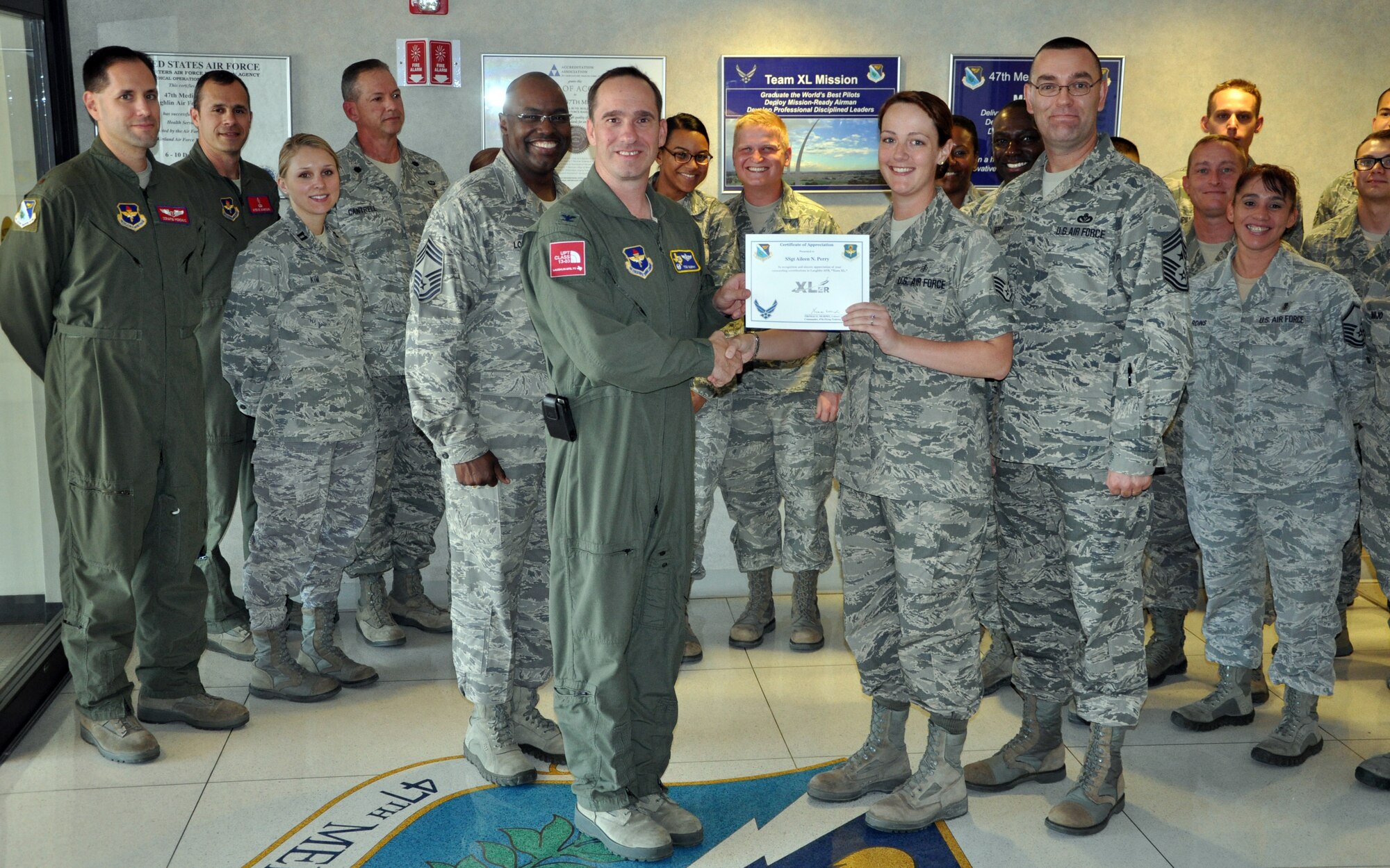Staff Sgt. Aileen Perry, 47th Medical Group education and training, poses with Col. Tom Murphy, 47th Flying Training Wing commander, and Chief Master Sgt. Garry Berry, 47th FTW command chief, after being presented the XLer of the week award at Laughlin Air Force Base, Texas, Oct. 3, 2012. The XLer is a weekly award chosen by wing leadership and given to those who consistently make outstanding contributions to Laughlin and their unit. (U.S. Air Force photo/2nd Lt. Daniel Brand)
