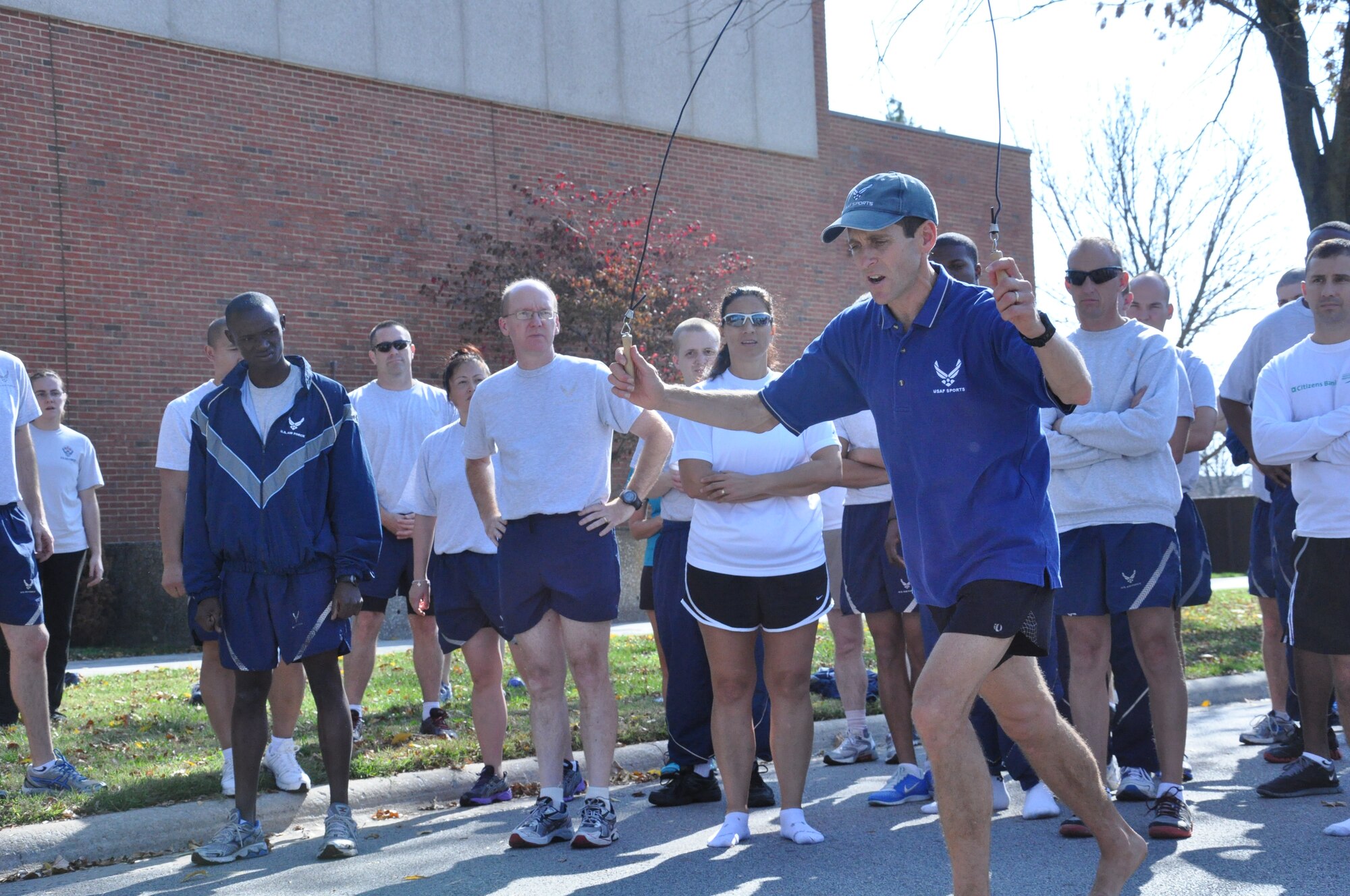 Lt. Col. Mark Cucuzzella, West Virginia University professor of family medicine and two time Air Force Marathon champion shows the crowd of participants different exercises that could help a runner with their posture and reduce pain. The three exercises that were taught to the members: slowly jogging in place focusing on landing closer to your center of mass; use a bicycle inner tube, and have someone hold it around the runner while they try to run away, which forces the runner to activate the glutes, he primary running muscle; and running with a jump rope, which forces the runner to spring, balance, posterize and not overstride.  (U.S. Air Force photo/Airman 1st Class Jake Eckhardt)
