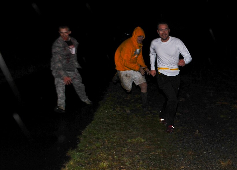 A participant in the Fairchild Airman's Running Team’s “zombie-themed” run dashes away as he is chased by an Airmen zombies at Fairchild Air Force Base, Wash., Oct. 30, 2012. The event started at 6 p.m. at the Funspot and afforded medical Airmen an opportunity to practice their skills with moulage makeup which is essential for effective mass casualty exercises. The run was approximately three-to-four miles long. (U.S. Air Force photo by Senior Airman Benjamin Stratton)