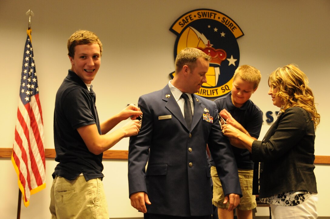 Family members adhere temporary chevrons to the sleeves of new Chief Master Sgt. Scott Anderson, superintendent of the 512th Force Support Squadron, who was promoted to the Air Force's highest enlisted rank in a ceremony Aug. 31, 2012, at Dover Air Force Base, Del. Shown are: (l to r) son, Joseph; son, Ethan; and wife, Dana. The Greenville, Maine, native joined the Air Force in 1995 and became a reservist in 2000. (U.S. Air Force photo by Chief Master Sgt. Matt Proietti)