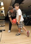 Pro Bowler Brian Voss instructs Angelo Ruisi, son of Krystal Ruisi, 59th Medical Logistics Readiness Squadron, on the proper mechanics of bowling during a PBA visit to Joint Base San Antonio-Lackland. (U.S. Air Force photo/Robbin Cresswell)