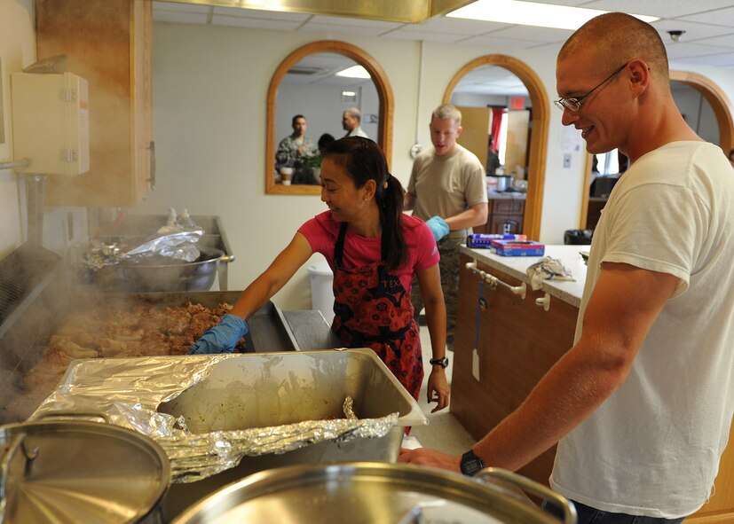 Komang Goins, SonLight Inn director, helps a volunteer prepare chicken during the SonLight Inn open house on Kunsan Air Base, Republic of Korea, Aug. 31, 2012 . This unique facility, managed by the Kunsan Chapel, is available daily to the Wolf Pack as a place to gather and socialize in a relaxed environment. (U.S. Air Force photo/Staff Sgt. Jonathan Fowler)