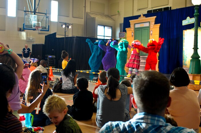 Sesame Street cast members wave goodbye to families after the Sesame Street/USO Experience for Military Families show Aug. 28, 2012 at Nellis AFB, Nev. Characters danced and discussed military issues like moving. (U.S. Air Force photo by Senior Airman Jack Sanders)