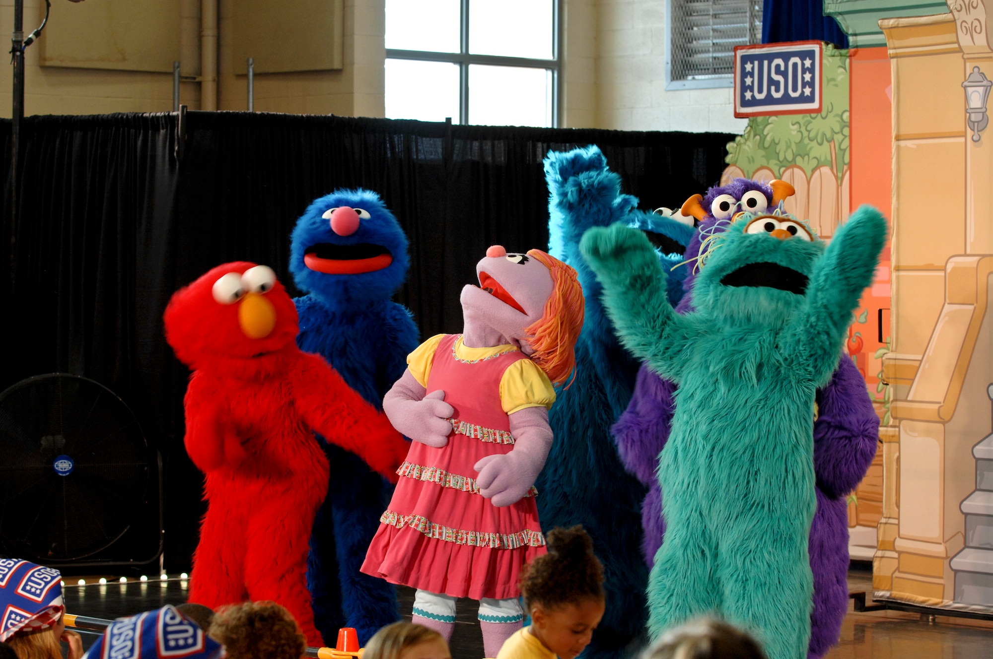 Sesame Street cast members laugh during a performance of the Sesame Street/USO Experience for Military Families show Aug. 28, 2012 at Nellis AFB, Nev. The show was helps military families cope with issues like moving. (U.S. Air Force photo by Senior Airman Jack Sanders)