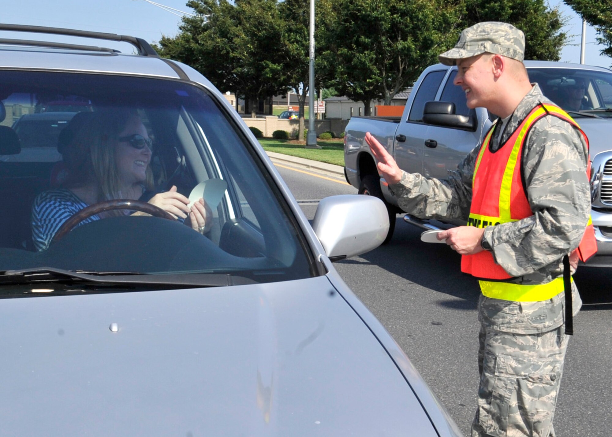 Lt. Col. Derek Salmi, director of safety with the 436th Airlift Wing, waves to Christin Michaud after handing her a sticker Aug. 31, 2012, at the front gate on Dover Air Force Base, Del. Members of the safety office handed out stickers and book bags to motorists as they departed for the Labor Day weekend as part of the 100 Critical Days of Summer Labor Day send-off. (U.S. Air Force photo by Tech. Sgt. Chuck Walker)