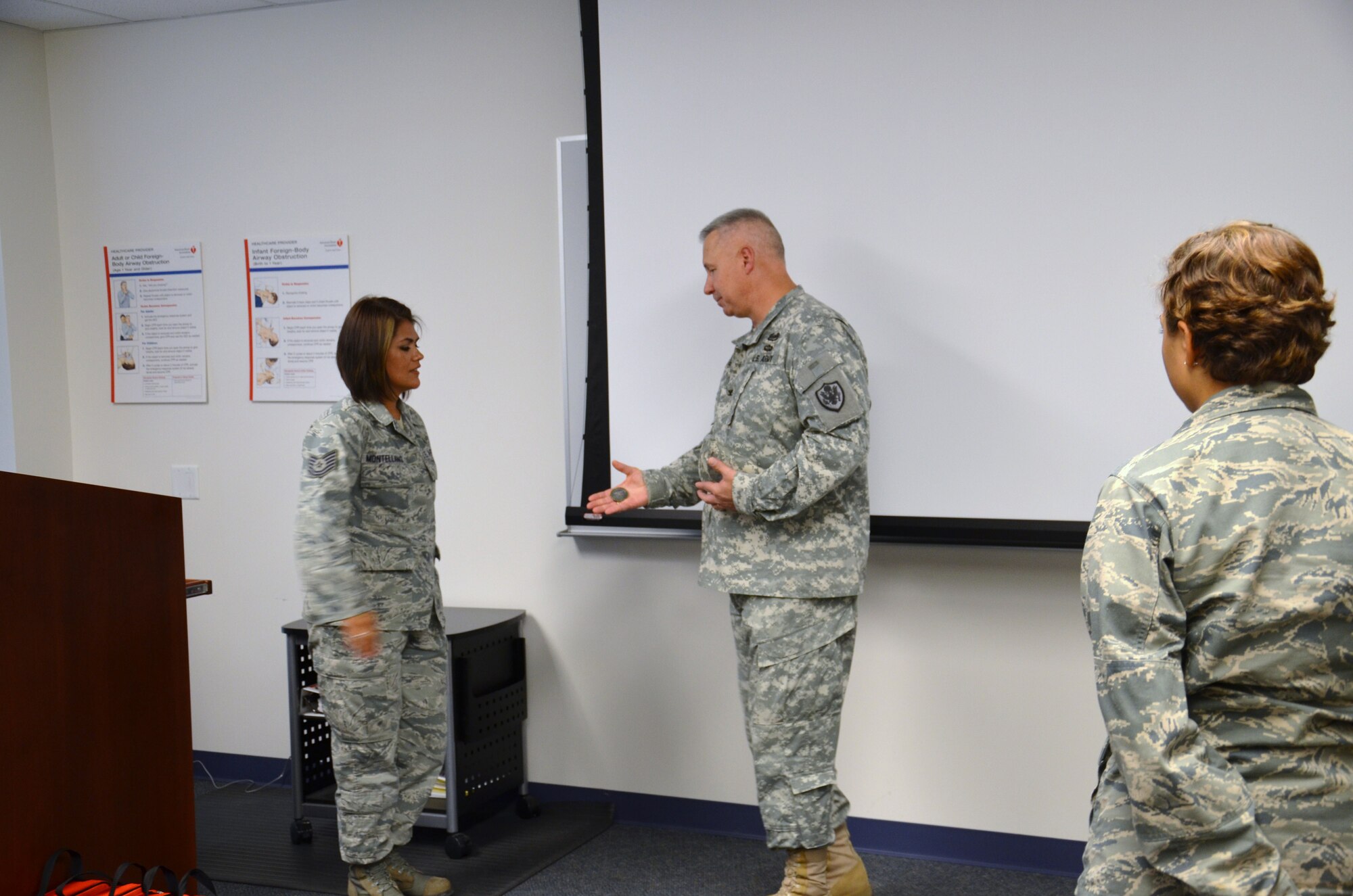 Tech Sgt. Valerie Montellano, instructor supervisor for the Air Force dental assistant program at the Medical Education and Training Campus, is surprised by Army Col. Robert Bridgford, vice commander of the 502nd Air Base Wing, while teaching a Basic Lifesaving class on Aug. 23.

Bridgford described to the class how Montellano’s training and quick thinking saved his life. He then presented Montellano with a coin while his wife, Shirley, presented her with a bouquet of flowers in appreciation for her actions that “brought him back to life”.

Bridgford collapsed while working out at the Jimmy Brought Fitness Center May 14. Montellano, along with a nurse with the AMEDDC&S Department of Nursing, immediately sprang into action and administered life support with an automated external defibrillator for approximately 15 minutes until emergency medical services arrived. According to Bridgford, if lifesaving measures were not performed within the first two minutes, he would not have survived.