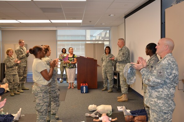 Tech Sgt. Valerie Montellano, instructor supervisor for the Air Force dental assistant program at the Medical Education and Training Campus, is surprised by Army Col. Robert Bridgford, vice commander of the 502nd Air Base Wing, while teaching a Basic Lifesaving class on Aug. 23.

Bridgford described to the class how Montellano’s training and quick thinking saved his life. He then presented Montellano with a coin while his wife, Shirley, presented her with a bouquet of flowers in appreciation for her actions that “brought him back to life”.

Bridgford collapsed while working out at the Jimmy Brought Fitness Center May 14. Montellano, along with a nurse with the AMEDDC&S Department of Nursing, immediately sprang into action and administered life support with an automated external defibrillator for approximately 15 minutes until emergency medical services arrived. According to Bridgford, if lifesaving measures were not performed within the first two minutes, he would not have survived.