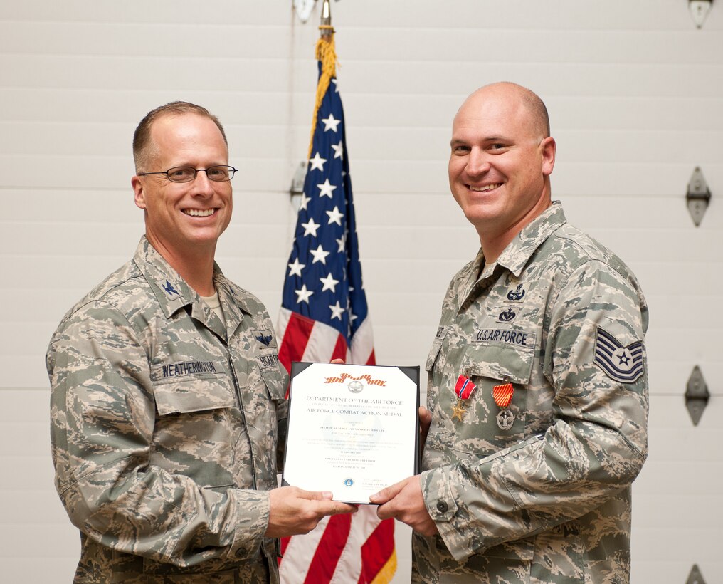 Col. Mark Weatherington, 28th Bomb Wing commander, presents Tech. Sgt. Nicholas Schulte, 28th Civil Engineer Squadron explosive ordnance disposal technician, with an Air Force Combat Action Medal Col. during a medal presentation ceremony at Ellsworth Air Force Base, S.D., Aug. 29, 2012. Schulte received both the Bronze Star and Combat Action Medal for his support in disposing 36 improvised explosive devices during Operation Enduring Freedom. (U.S. Air Force photo by Airman 1st Class Alystria Maurer/Released) 
