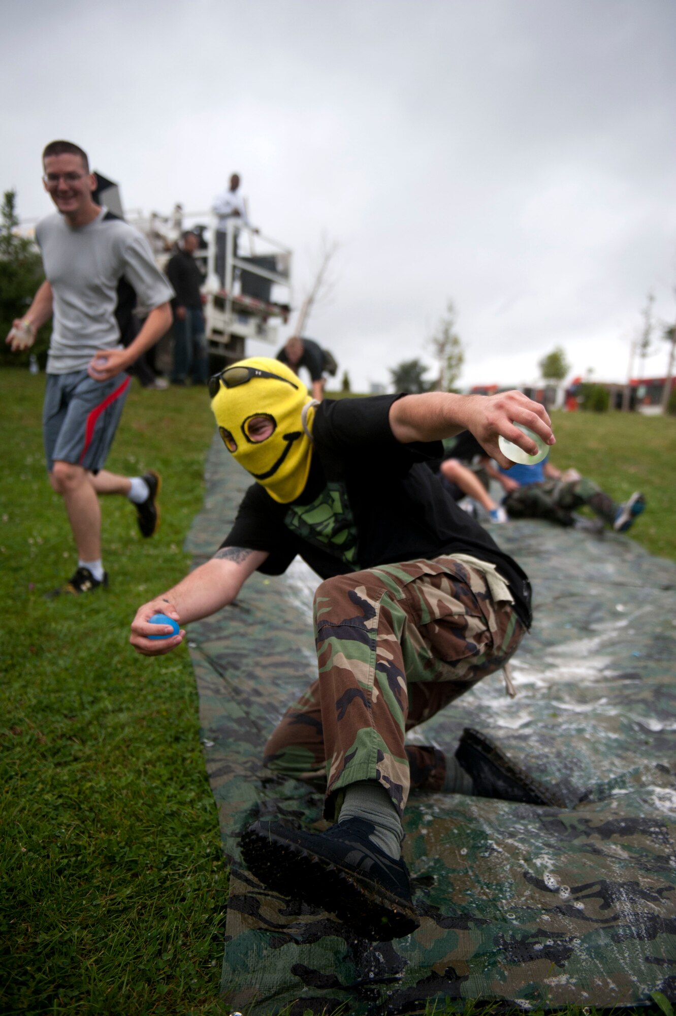SPANGDAHLEM AIR BASE, Germany – Senior Airman Jared Egia, 52nd Civil Engineer Squadron structural journeyman, slides down a hill holding water balloons during a 52nd Logistics Readiness Squadron zombie 5K fundraiser here Aug. 31.  Base members dressed as zombies and chased runners, who competed for time against other groups to complete a series of obstacles.  Water balloons were used as simulated ammunition players could use against the zombie horde to get away safely.  (U.S. Air Force photo by Airman 1st Class Gustavo Castillo/Released)