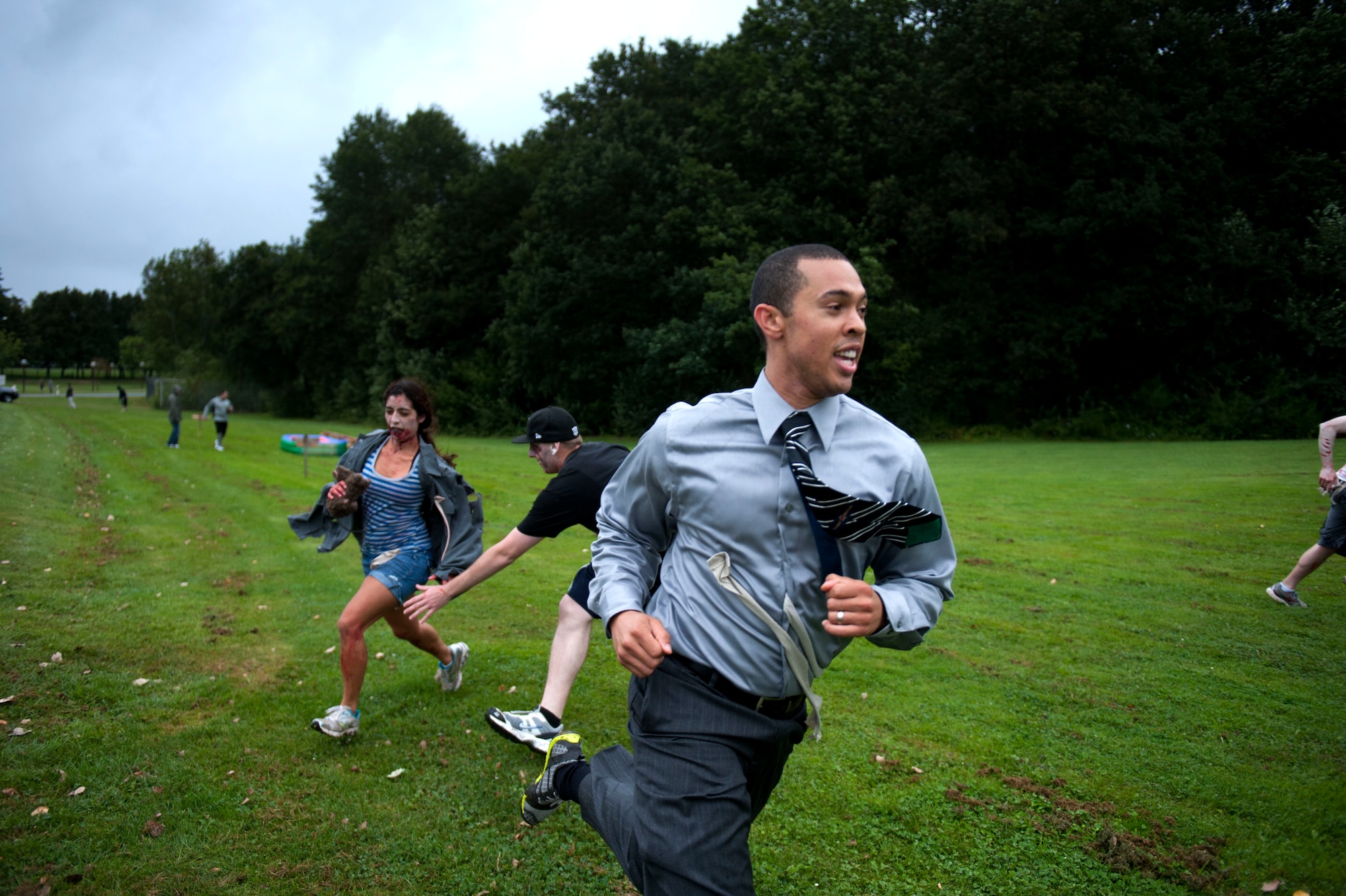 SPANGDAHLEM AIR BASE, Germany – Capt. John Perry, 726th Air Mobility Squadron aerial port flight commander, dashes across a field of zombies during a 52nd Logistics Readiness Squadron zombie 5K fundraiser here Aug. 31.  Base members dressed as zombies and chased runners, who competed for time against other groups to complete a series of obstacles.  Players were outfitted with pieces of fabric to represent lives.  Once a runner was out of lives, they became a zombie, and chased runners who crossed their path. (U.S. Air Force photo by Airman 1st Class Gustavo Castillo/Released)