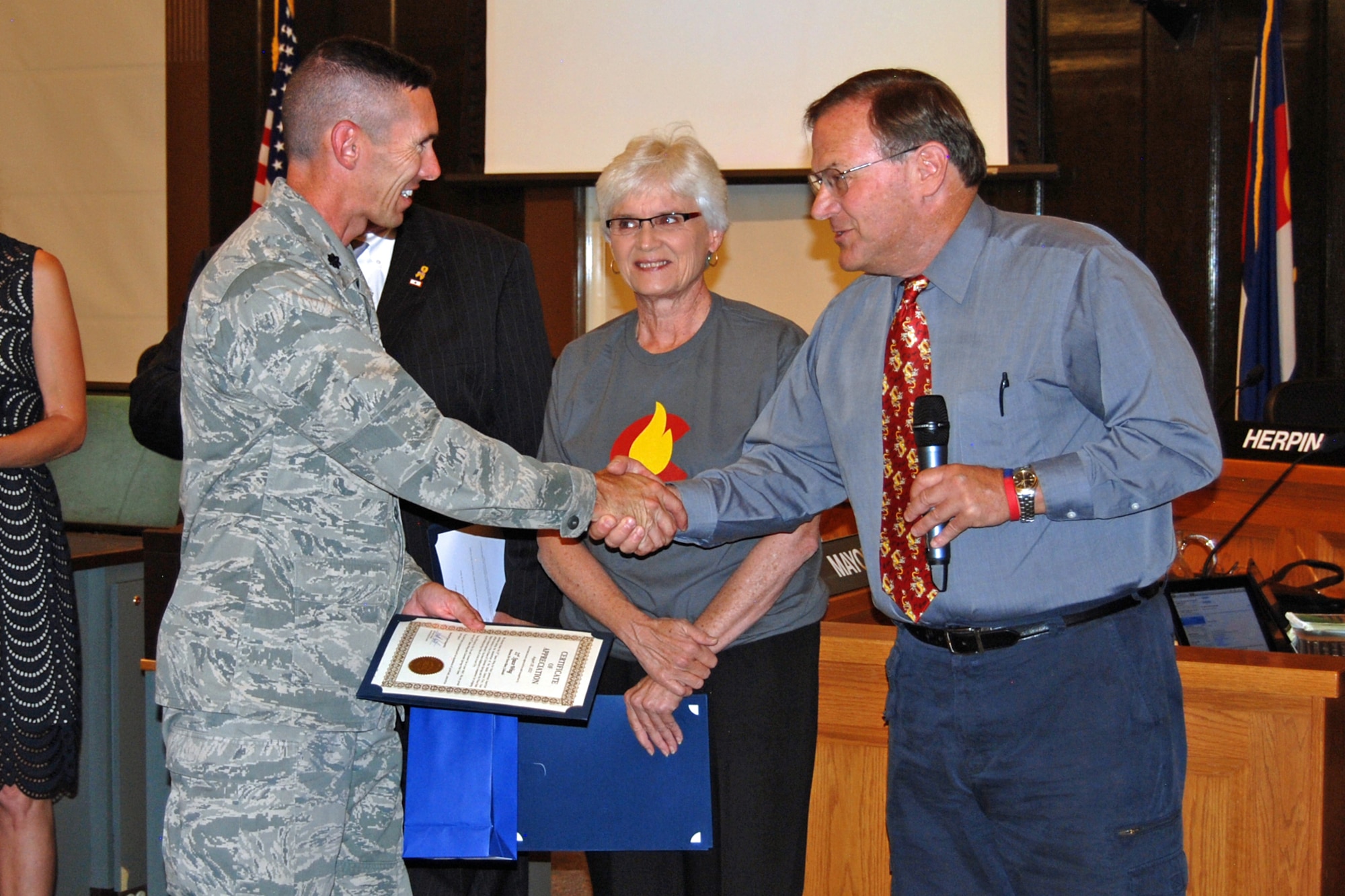 Lt. Col. Roger Sherman, 16th Space Control Squadron commander, accepts a certificate of recognition Aug. 28 from Scott Hente, Colorado Springs city council president, on behalf of the 21st Space Wing for volunteer efforts related to the Waldo Canyon fire recovery. Volunteers from more than two dozen area military organizations volunteered more than 1,300 hours as part of the recovery, helping with trash removal, traffic control, working with Army Corps of Engineers in making a sand bagging video for future natural disasters, and debris removal from destroyed homes. The fire broke out June 23 west of Manitou Springs, and over the course of several days spread north and east, burning into Colorado Springs, destroying 346 homes. At the peak of the fire, more than 35,000 residents, including many military families, were evacuated from their homes. (U.S. Air Force photo/Lea Johnson)