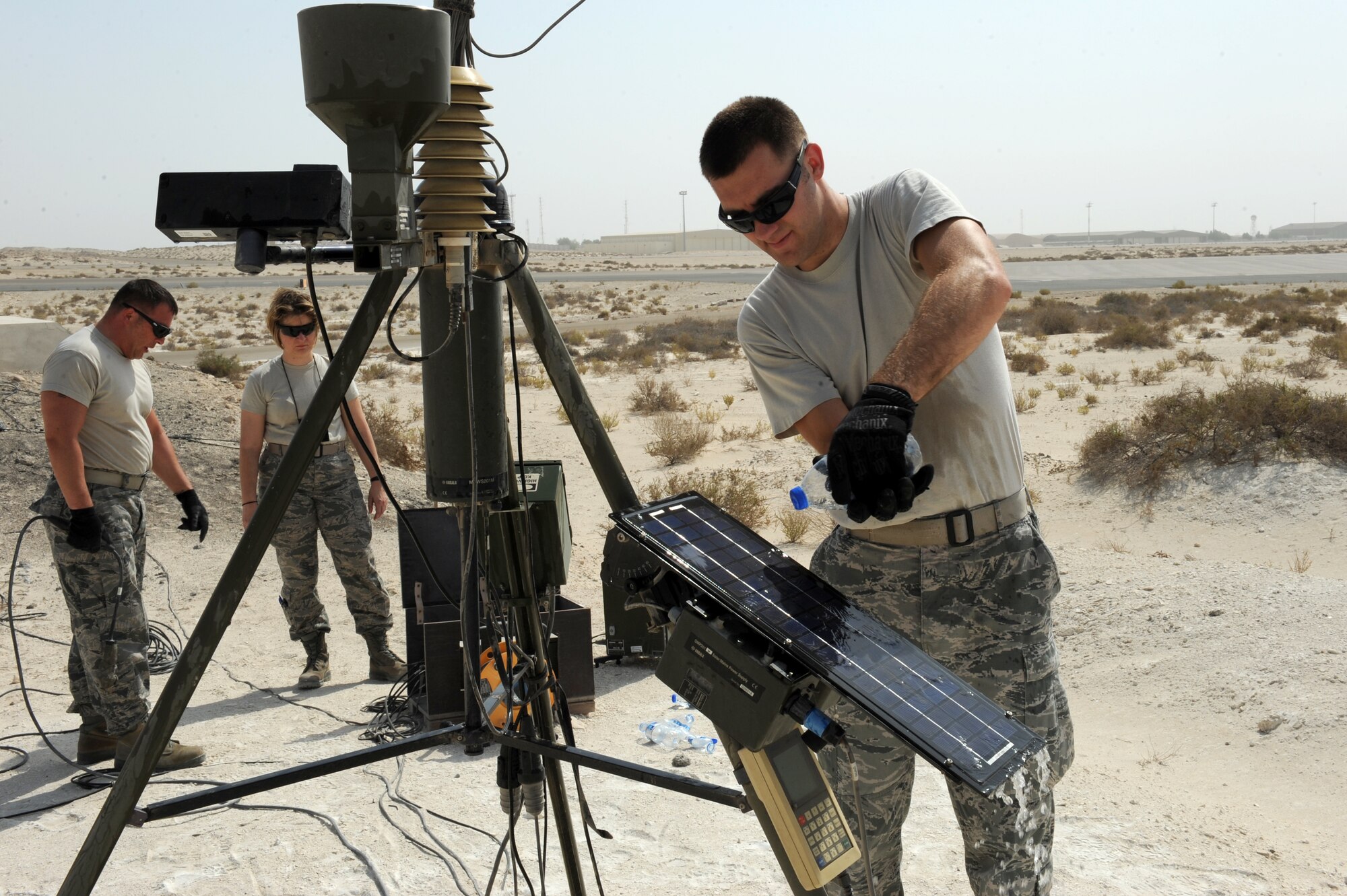 SOUTHWEST ASIA - U.S. Air Force Staff Sgt. Christopher Bieber, 380th Expeditionary Operations Support Squadron weather flight technician, pours water on a panel of a TMQ-53 tactical weather observation station as Master Sgt. Don Milliman, weather flight NCO in charge, and Maj. Jeanne Szczes,  weather flight commander, inspect cables during a periodic maintenance inspection Aug. 31, 2012. The weather flight conducts PMIs on their equipment monthly. (U.S. Air Force photo/Master Sgt. Scott MacKay)
