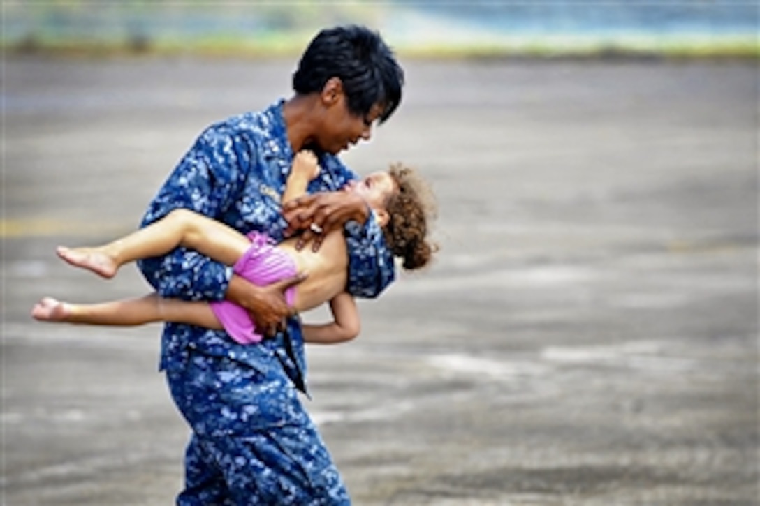 Navy Lt. Lori Campbell carries a young girl to safety on Naval Air Station Joint Reserve Base New Orleans, La., Sept. 1, 2012. The girl was medically evacuated from Port Sulphur, La., by members of the Louisiana Army National Guard's 2-135th General Support Aviation Battalion.