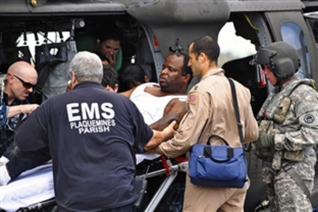 Army Staff Sgt. Gary Cheek assists Navy and Plaquemines Parish Emergency Management Services personnel as they prepare a man for medical transfer at Naval Air Station Joint Reserve Base New Orleans, La., Sept. 1, 2012, as part of Hurricane Isaac recovery operations. Cheek is assigned to the 1st Assault Battalion, 244th Aviation Regiment, Louisiana National Guard. 