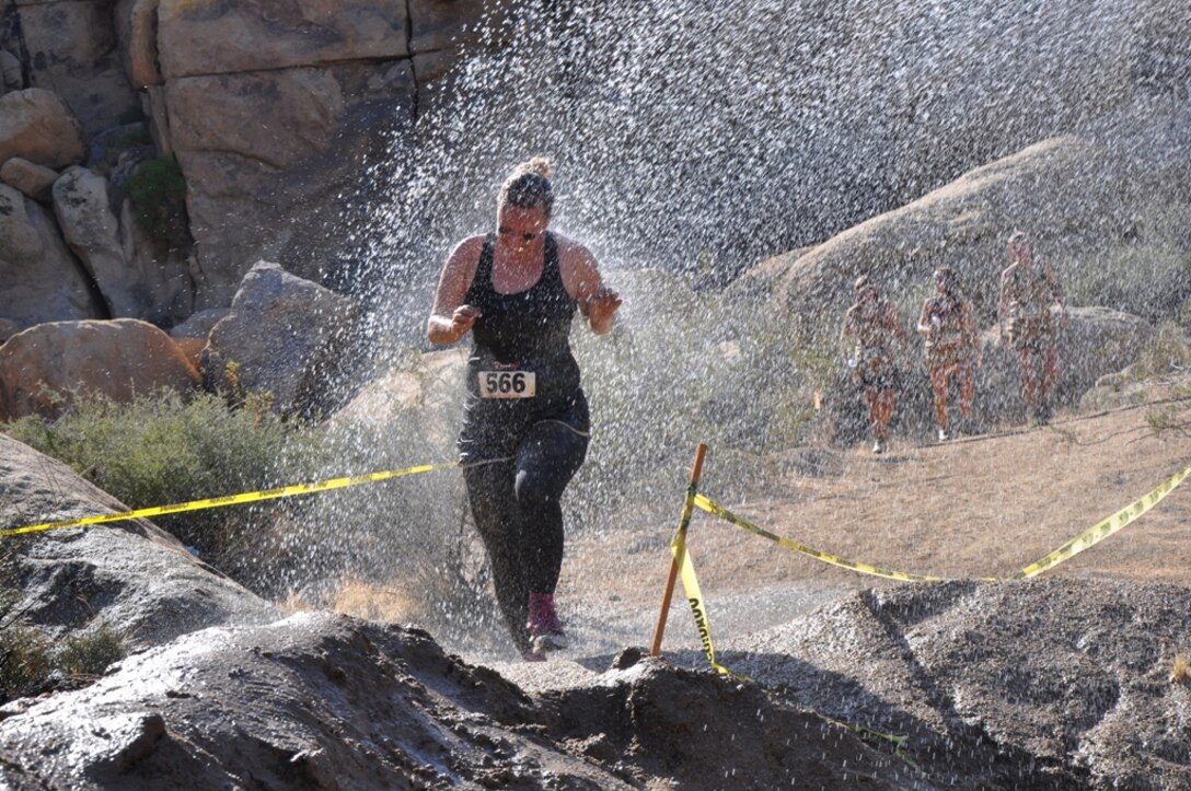 Jessica Mcghee, a participant of the 4th Annual Rockin’ the High Desert Mud Run in Apple Valley, Calif., runs through a shower of water during the event Aug. 25. As participants ran the course, they were put through tough obstacles as they slipped and slid through the 5K course. Participants tackled mud pits, hurdles, ladders, slides, walls and an ice bath.  Photo by Pfc. Norman Eckles 