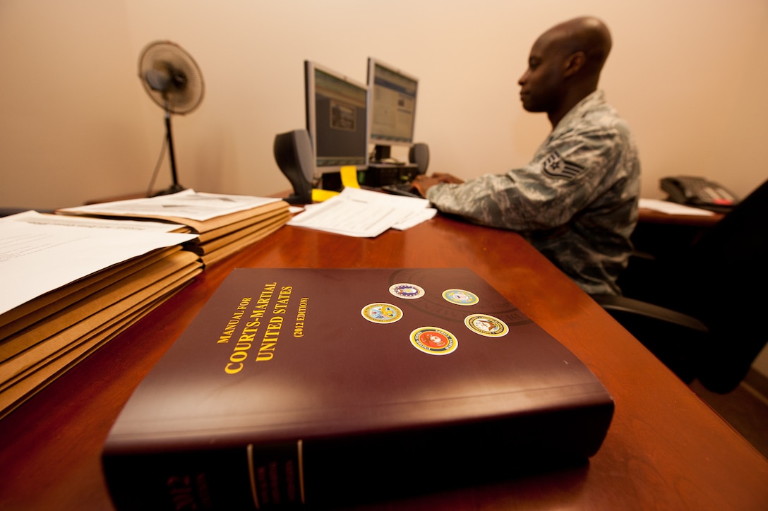 Staff Sgt. Charles Holiness, 28th Bomb Wing Judge Advocate military justice adverse actions NCO in charge, enters information into the automated military justice analysis and management system after referencing the manual for courts-martial at the legal office on Ellsworth Air Force Base, S.D., Sept. 4, 2012. Airmen from the base Legal Office provide services to military members as well as eligible civilians. (U.S. Air Force photo by Airman 1st Class Kate Thornton-Maurer)