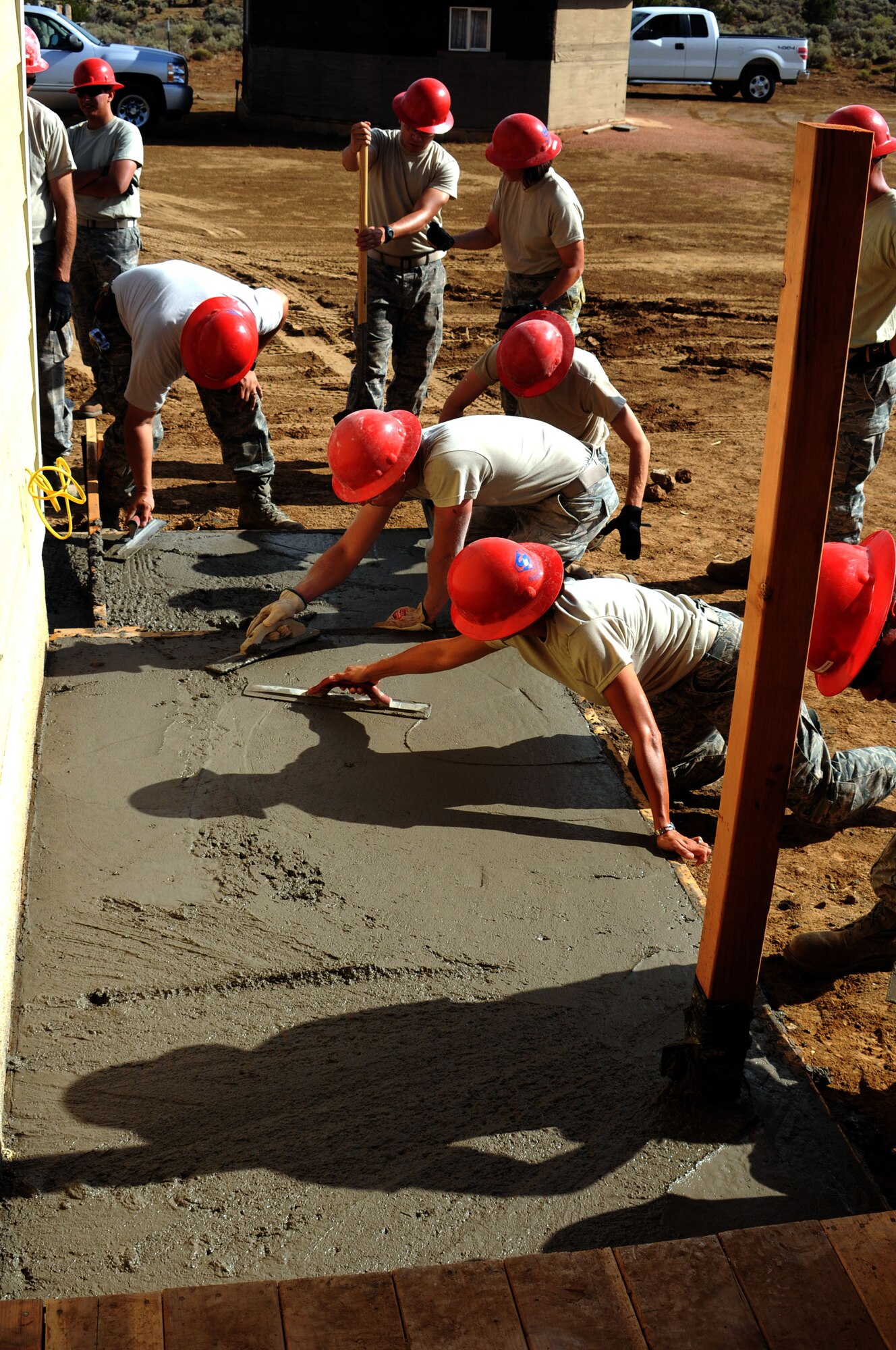 The 210 RED HORSE members lay and spread a cement walkway. 