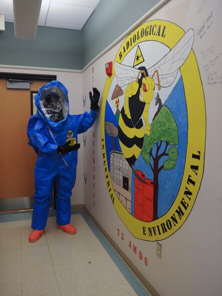 U.S. Air Force Airman 1st Class Christopher Cameron, 23d Aerospace Medicine Squadron bioenvironmental engineer, poses next to the AMDS emblem at Moody Air Force Base, Ga., Aug. 30, 2012. Airmen of the 23d AMDS ensure the safety of the base by testing the air, water and soil. (U.S. Air Force photo by Airman 1st Class Olivia Dominique/Released)