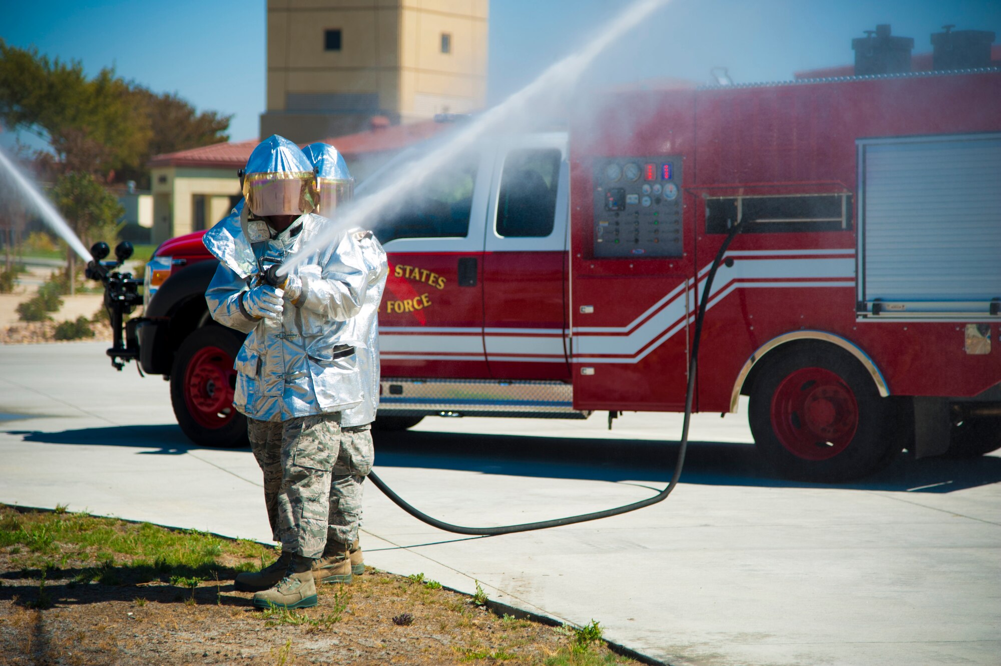 Airman 1st Class Patrick O'Toole and Airman 1st Class Jake Chung and Jason Root, 60th Civil Engineer Squadron fire emergency services firefighters, use a hose to train in sparying a fire Tuesday to stay proficient in case of an emergency. (U.S Air Force photo/Airman 1st Class Nicole Leidholm)