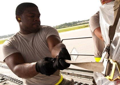Airman 1st Class Melvin Hamilton, 437th Aerial Port Squadron  air transportation journeyman, tightens a pallet strap Aug. 29, 2012, at Joint Base Charleston – Air Base, S.C. The pallets contained food and medical supplies destined for Soto Cano Air Base, Honduras. (U.S. Air Force photo by Staff Sgt. Katie Gieratz)