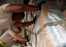 Airman 1st Class Melvin Hamilton, 437th Aerial Port Squadron air transportation journeyman, assists two other APS air transportation journeymen as they push a pallet onto a L100 aircraft Aug. 29, 2012, at Joint Base Charleston – Air Base, S.C. The pallets contained food and medical supplies to assist the U.S. embassy Soto Cano, Honduras. (U.S. Air Force photo by Staff Sgt. Katie Gieratz)