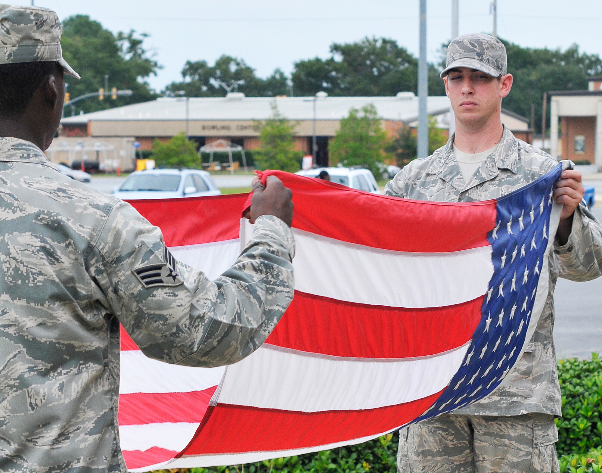 L-R, Senior Airman Arthur Burney, 78th Air Base Wing SCSE, and Senior Airman MacKenzie Thompson, 54th CBCS, fold the flag during retreat Aug. 30.  (U. S. Air Force photo/Sue Sapp)