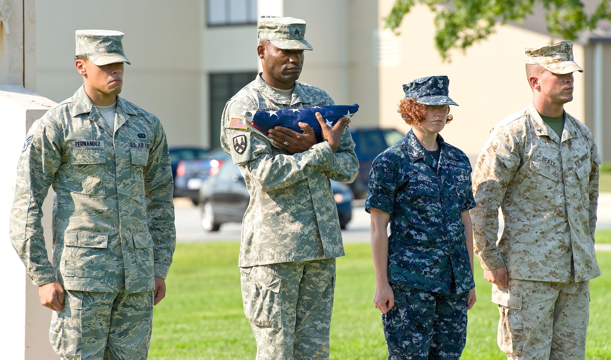 Senior Airman Joshua Fernandez, left, dress and restoration specialist; Army Sgt. Calvester Herlong, Army liaison team; Navy Petty Officer 1st Class Jennifer Howell, Navy and Marine Corps liaison; and Marine Lance Cpl. Landon Beatty, Marine Corps liaison, secure the flag during retreat at the base flag pole Aug. 31, 2012, at Dover Air Force Base, Del. The Air Force Mortuary Affairs Operations flag-folding detail represented all branches of the Department of Defense. (U.S. Air Force photo by Roland Balik)
