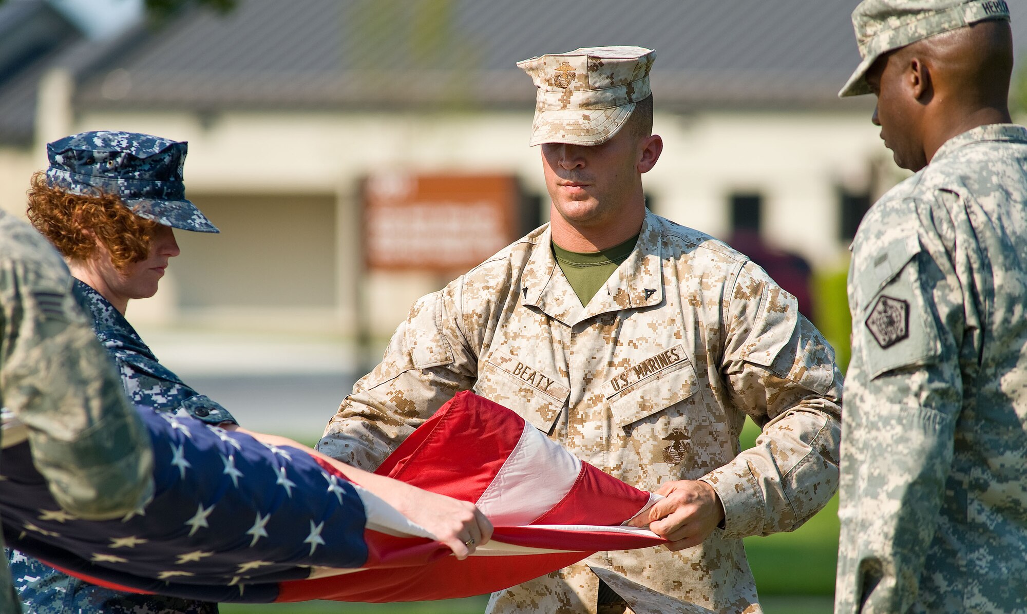 Navy Petty Officer 1st Class Jennifer Howell, left, Navy and Marine Corps liaison; Marine Lance Cpl. Landon Beatty, Marine Corps liaison; and Army Sgt. Calvester Herlong, Army liaison team, fold the flag during retreat at the base flag pole Aug. 31, 2012, at Dover Air Force Base, Del. (U.S. Air Force photo by Roland Balik)