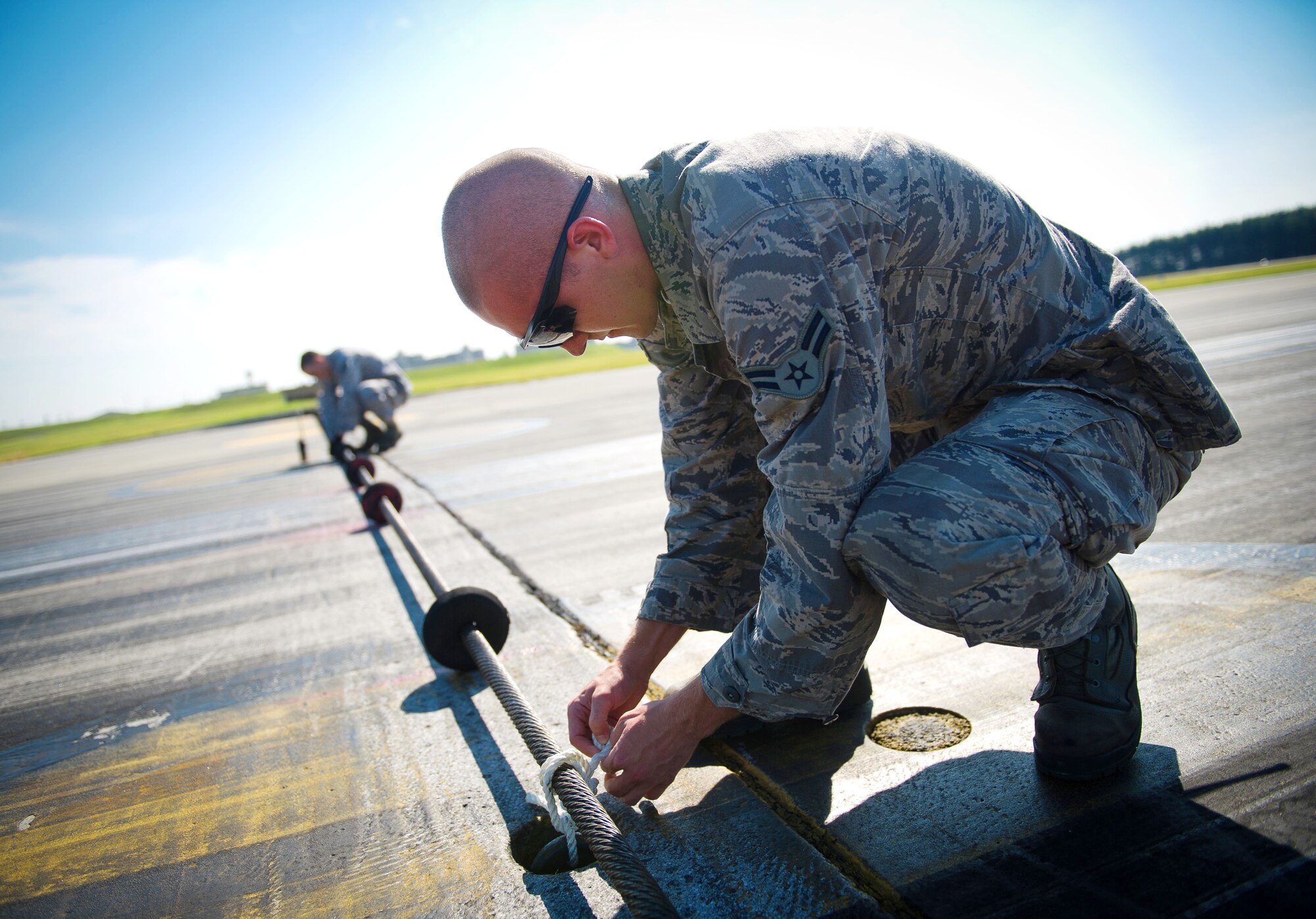 YOKOTA AIR BASE, Japan -- Airman 1st Class Johnathan Riley, 374th Civil Engineer Squadron electrical power productions technician, inspects an emergency aircraft landing cable on the runway at Yokota Air Base, Japan, on Sept. 5, 2012. These inspections are part of a routine checklist that power productions technicians must accomplish weekly, monthly and yearly. (U.S. Air Force photo by Staff Sgt. Chad C. Strohmeyer)