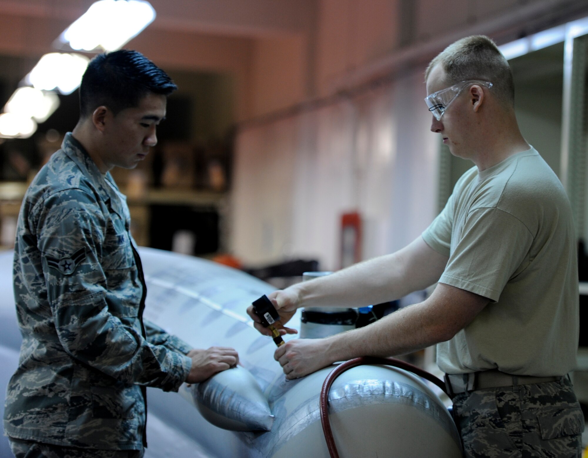 U.S. Air Force Airmen 1st Class Zach Gribble and Darrel Wang, 18th Operations Support Squadron aircrew flight equipment apprentices, inflate an E-3 Sentry Evacuation Assembly Slide on Kadena Air Base, Japan, Sept. 5, 2012. An aircraft life raft escape slide assembly is used for evacuating passengers from an aircraft and providing a floating support if the evacuation happens over water.  It has an inflatable slide structure, which is connected to an inflatable boarding slide structure to define an integral unit, while each structure is still independently inflatable. (U.S. Air Force photo/Airman 1st Class Justin Veazie)